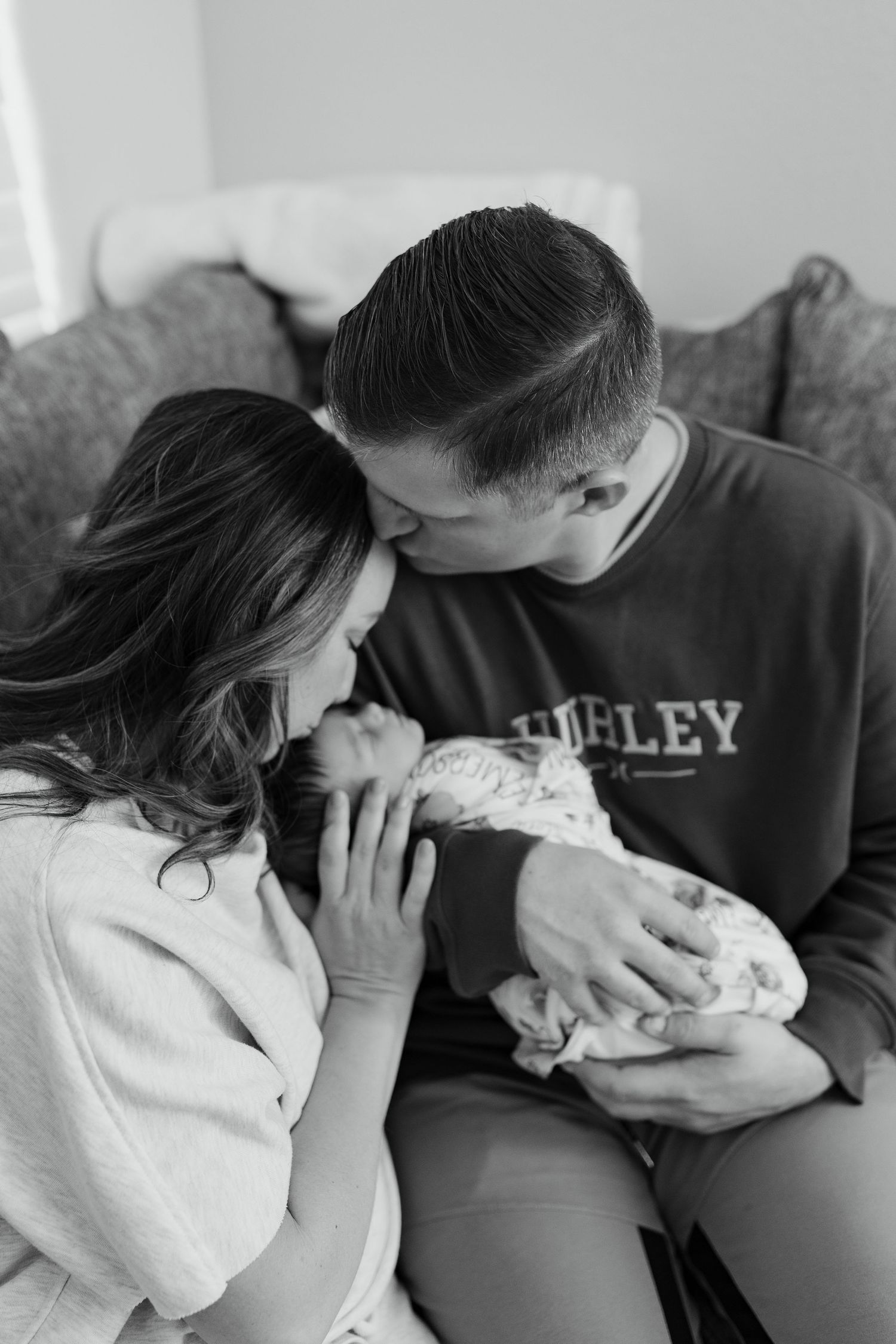 black and white image of a man and woman looking at their newborn baby