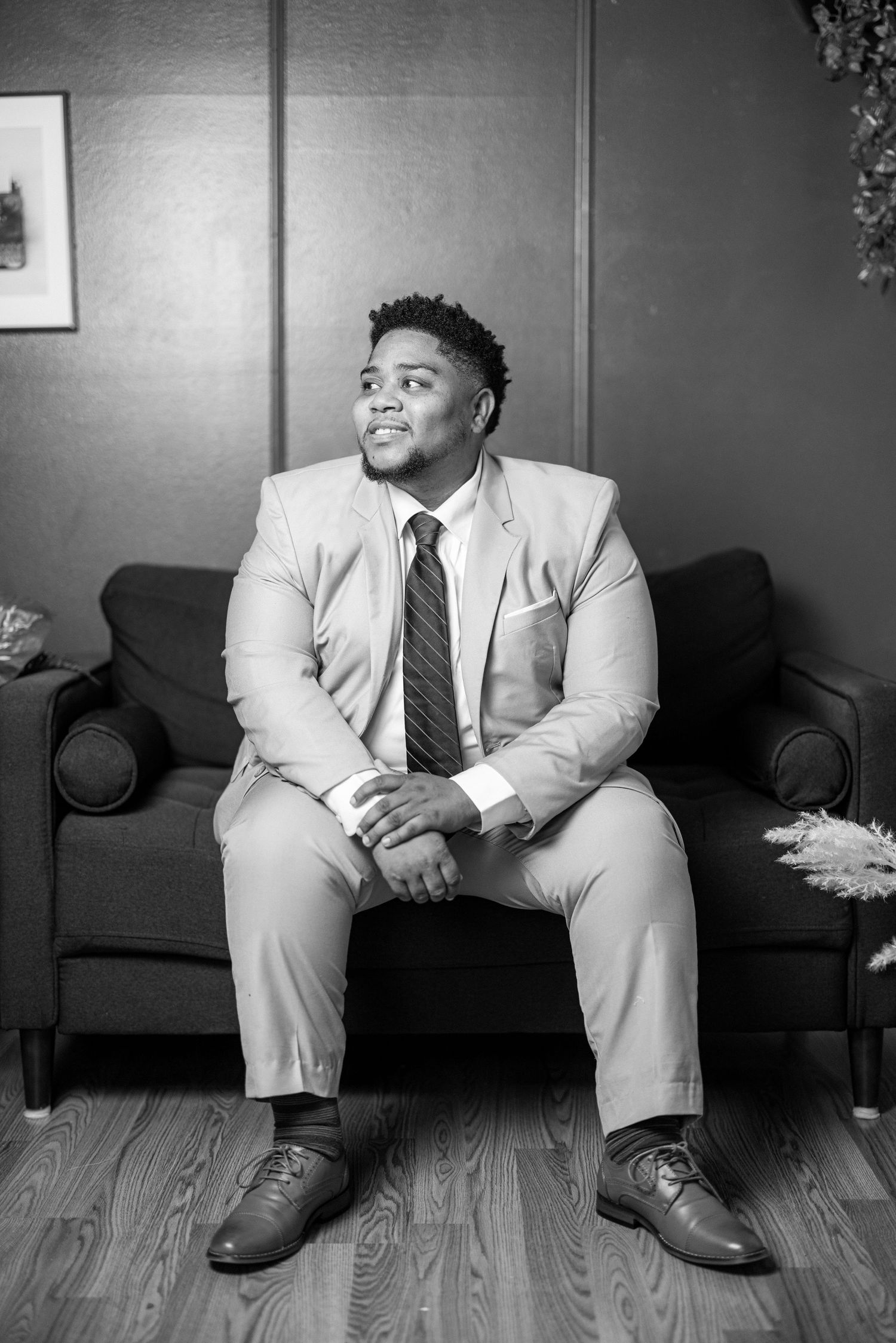 A series of black and white photos showing someone in a light-colored suit seated on a couch in various poses.