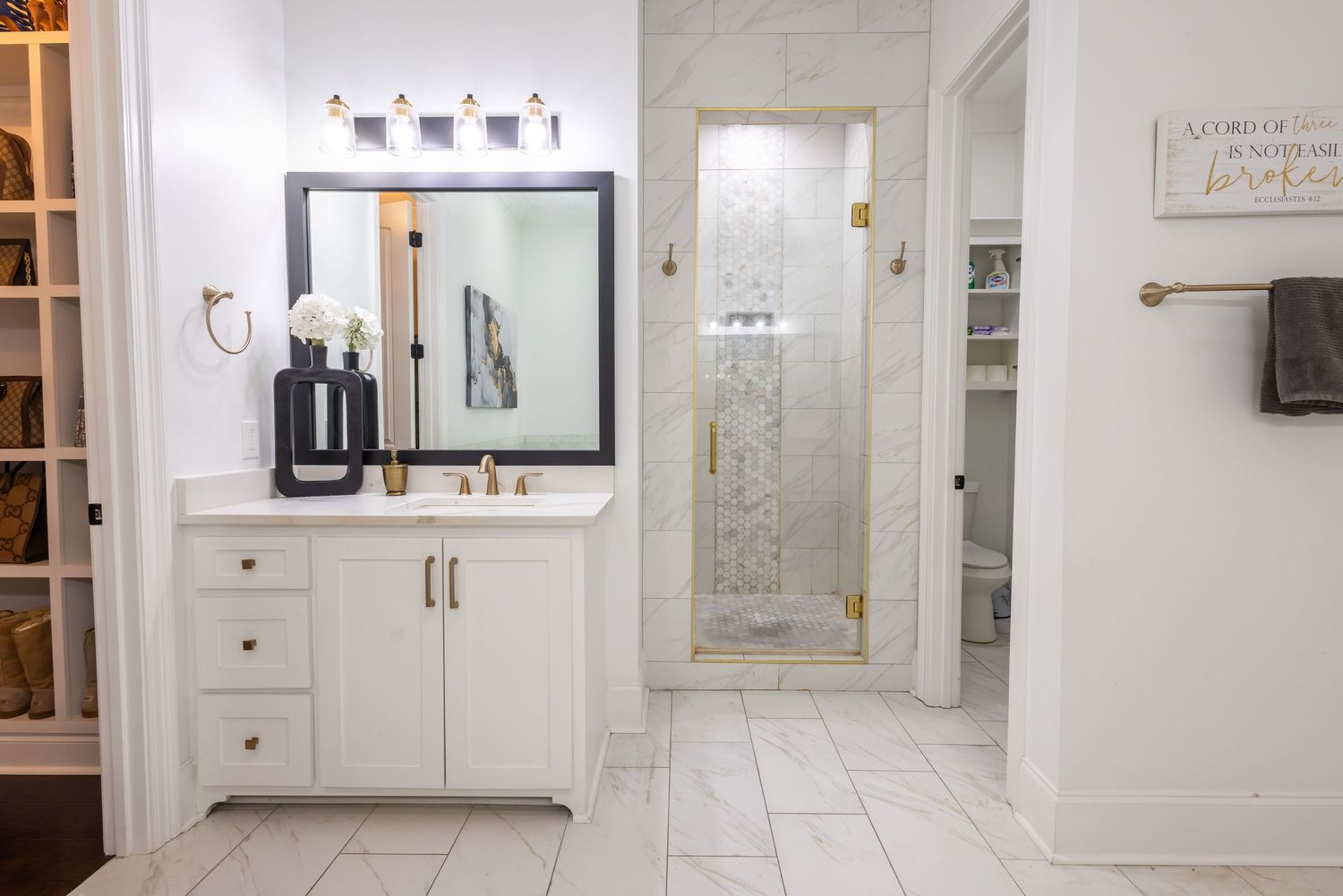 Elegant white kitchen with marble countertops, gold hardware, and glass-front cabinets showcases classic design elements.