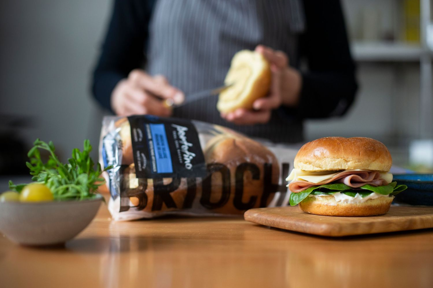 person in a chefs apron making a sandwich