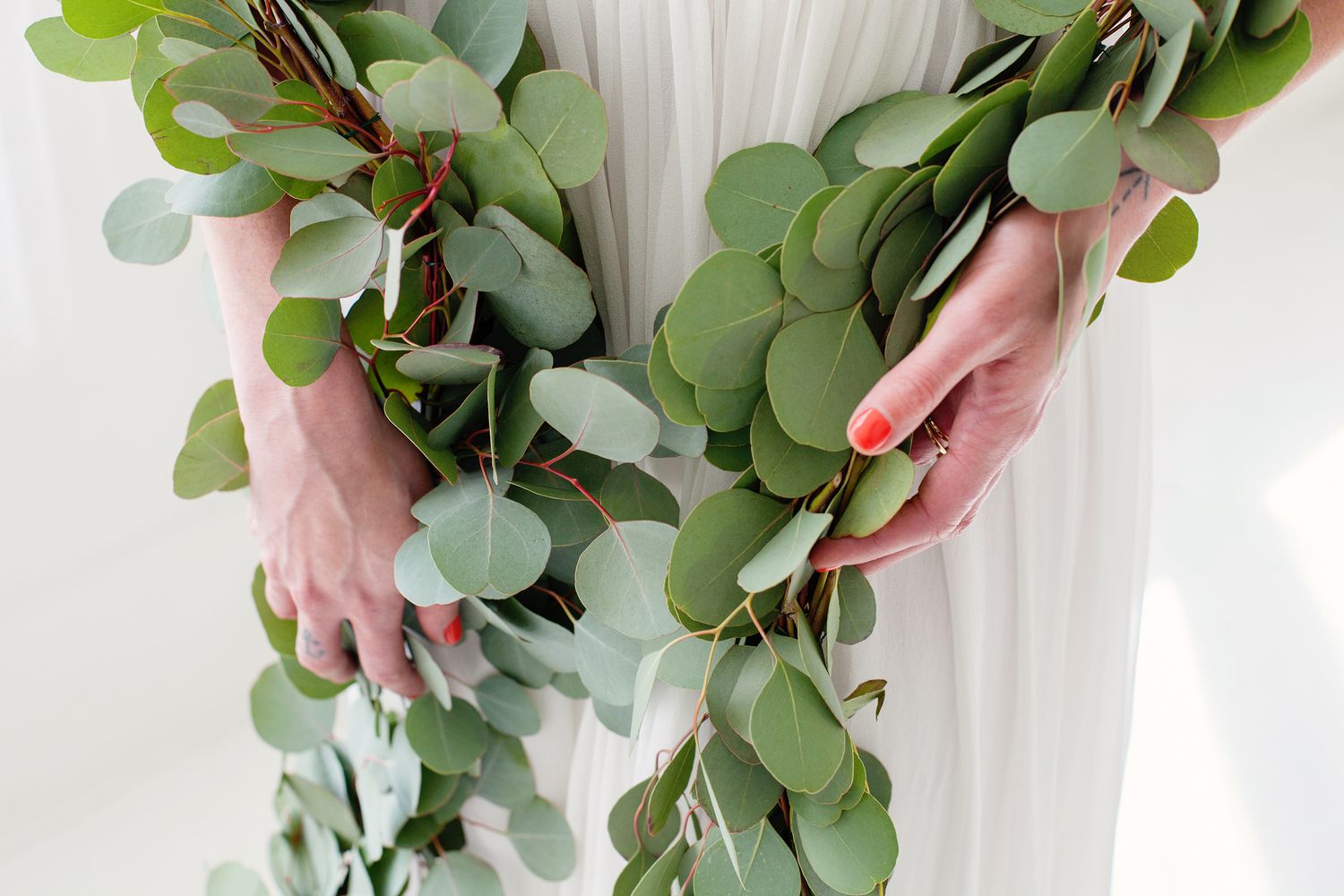 detail of womans hands holding a eucalyptus around her waist