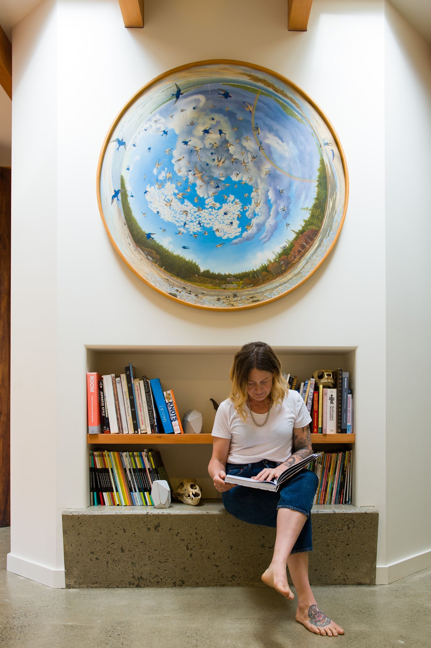 A woman sits reading under a circular shaped painting
