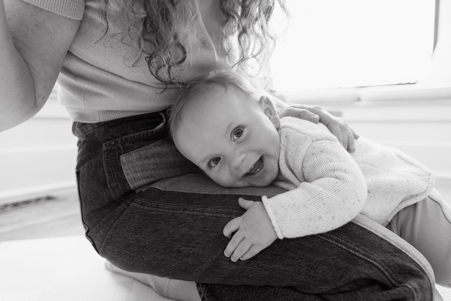 Laughing baby on mom's lap looking at the camera