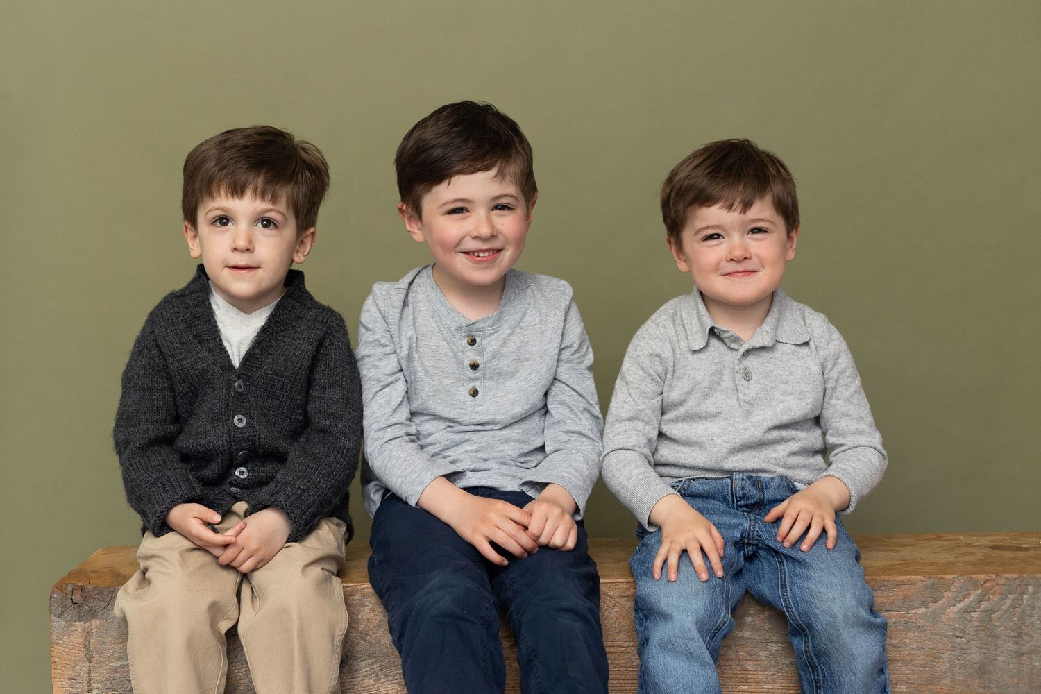 Three cute brother posing for a photograph with a green background