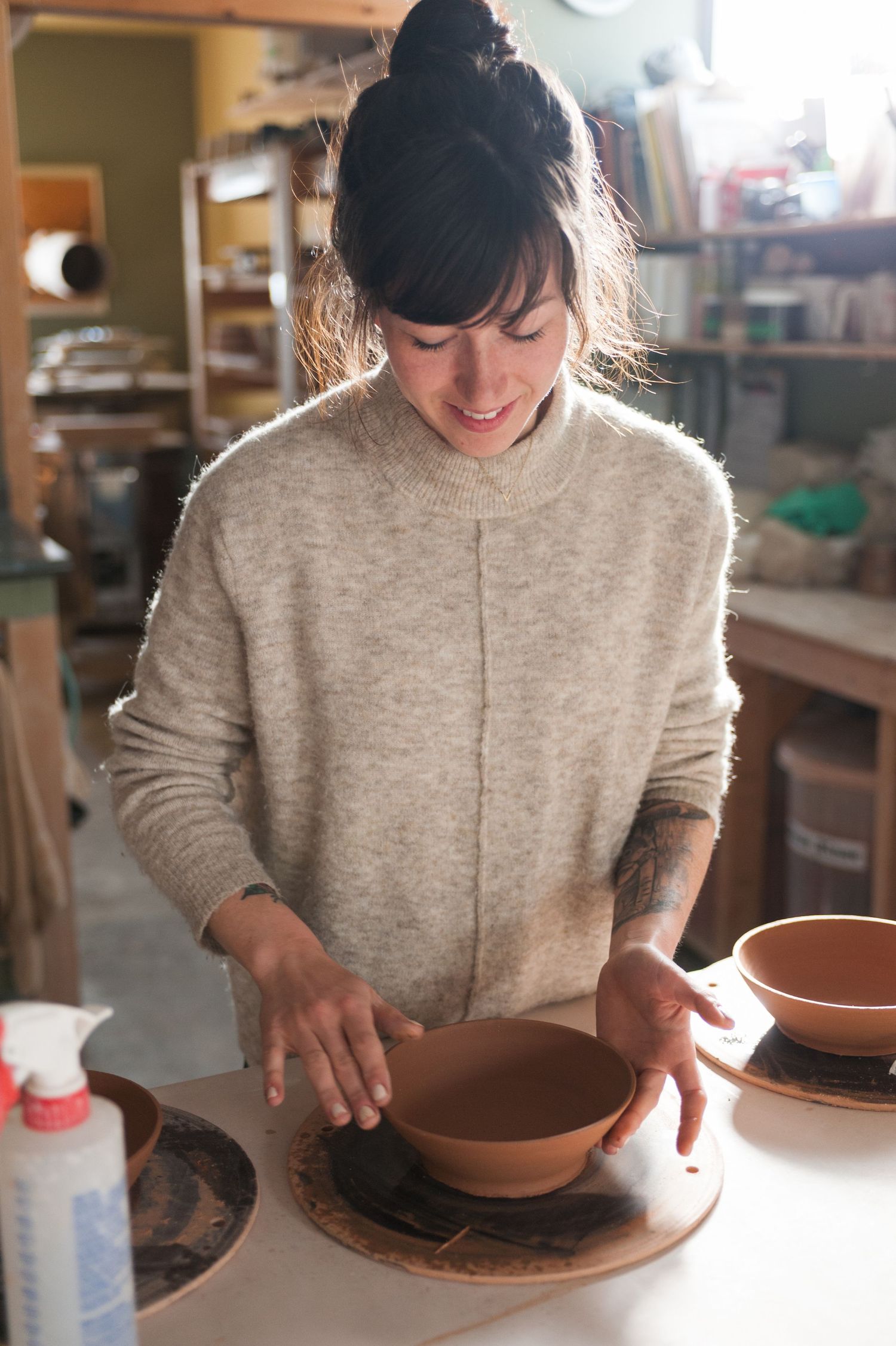 Brunette woman in a ceramics studio preparing a bowl to be placed in a kiln
