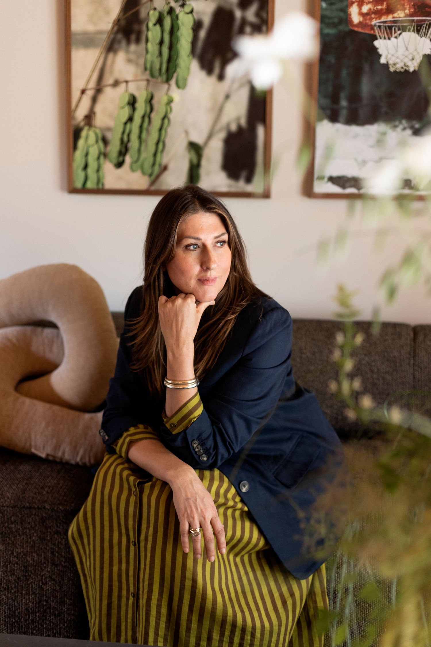 Pensive woman in a striped dress sitting on an elegant sofa