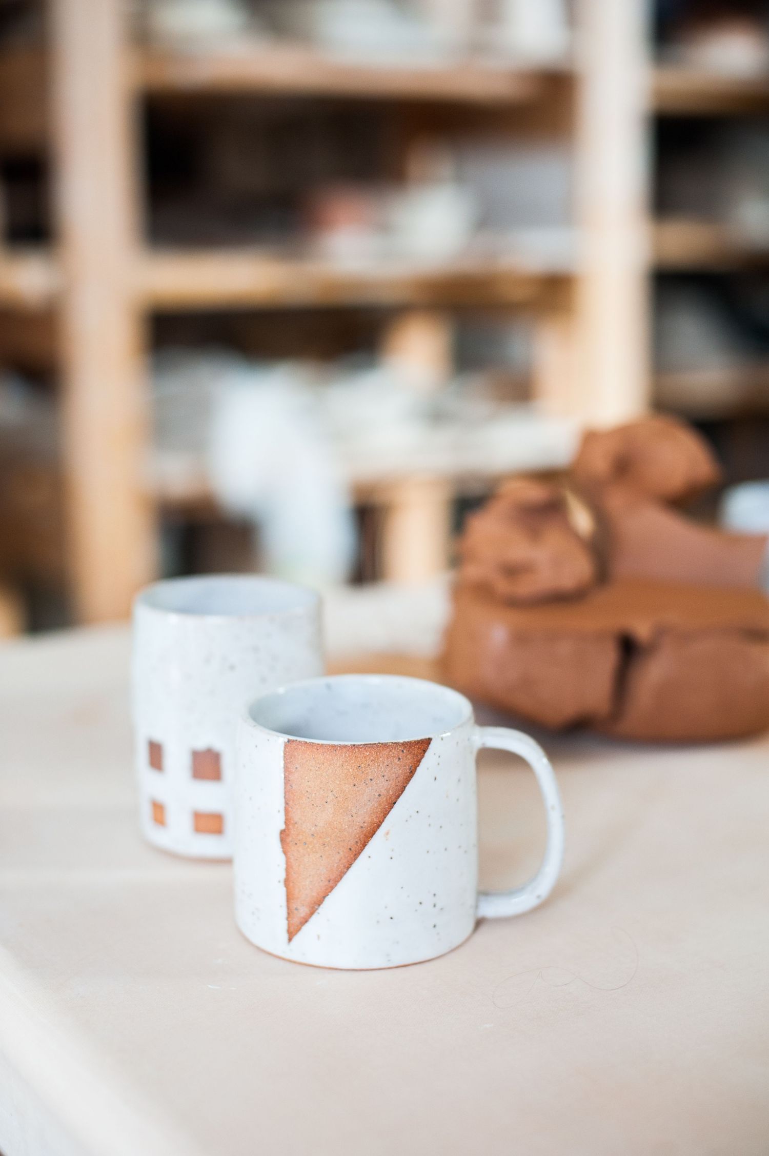 Coffee cup on a ceramics studio with a lump of clay in the background