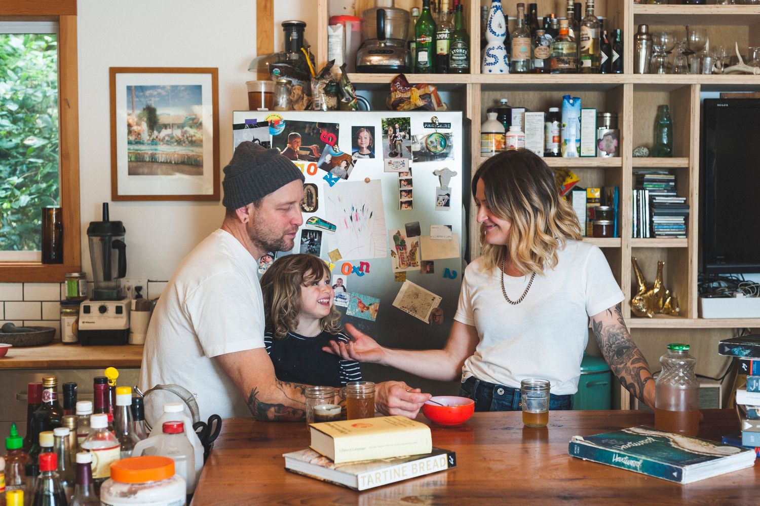 woman and man with a young daughter sharing a happy moment in their kitchen