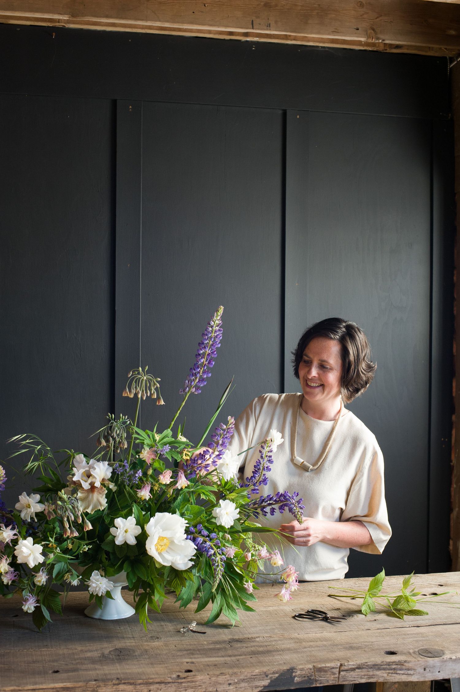 Woman in a floral studio place a flower in a bouquet