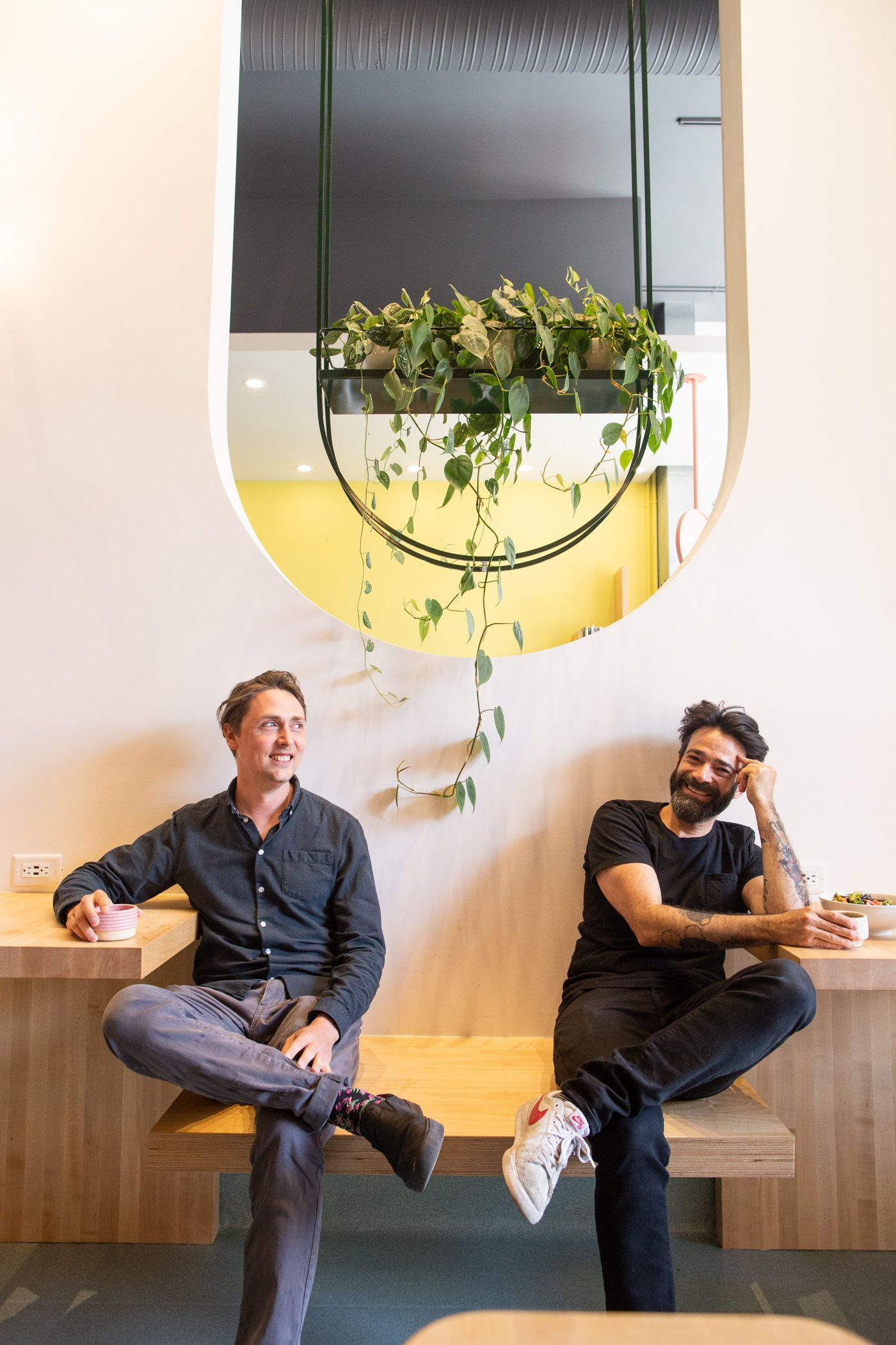 Two men in a coffee shop laughing as they drink coffee