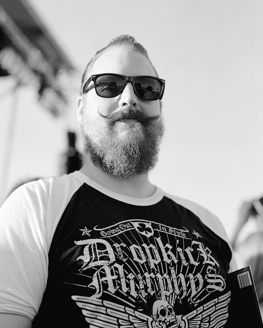 black and white portrait of a man with a moustache. he is wearing a dropkick murphy's tee shirt.