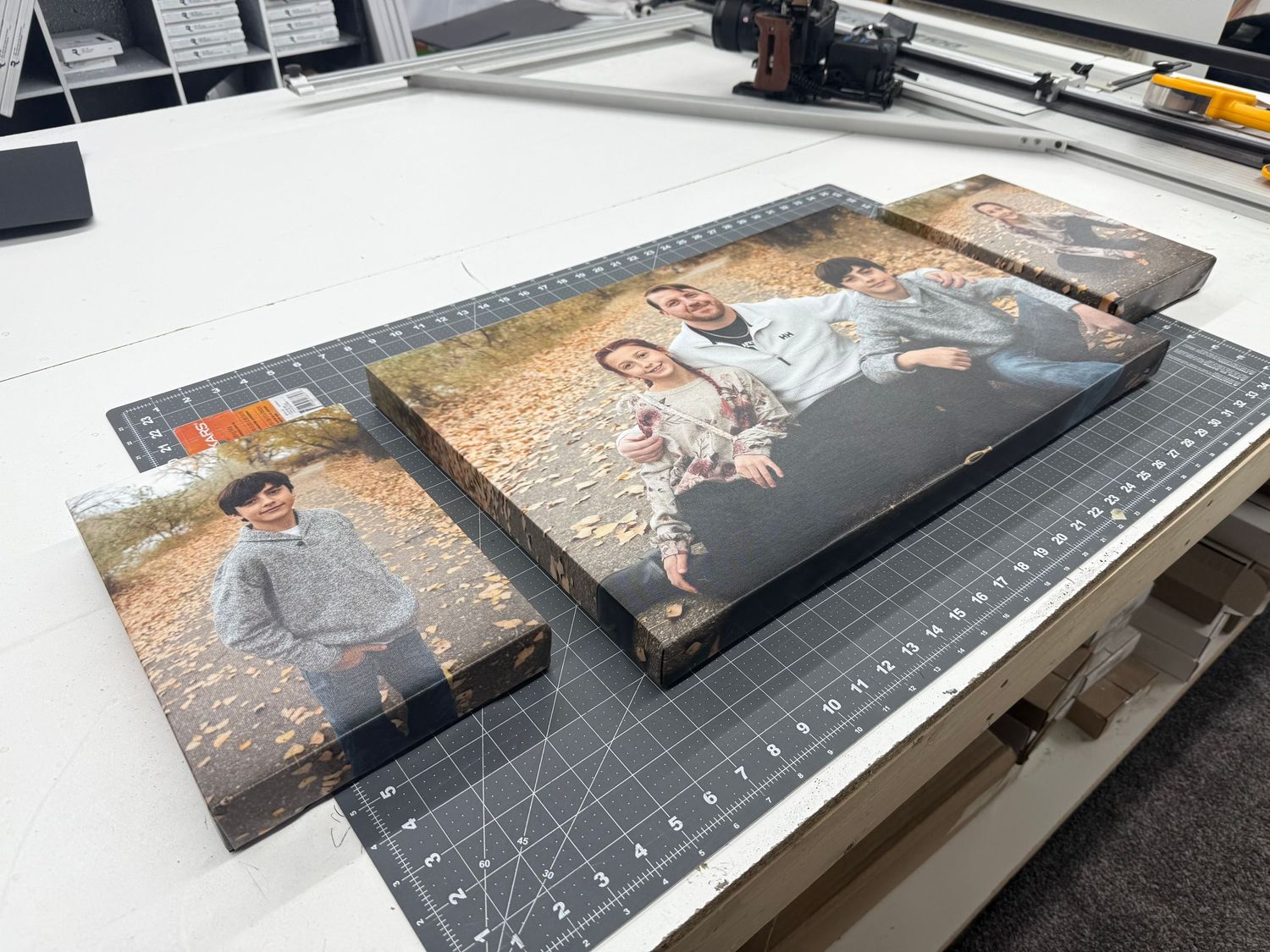 Two canvas prints of a couple embracing outdoors among autumn leaves on a cutting mat.
