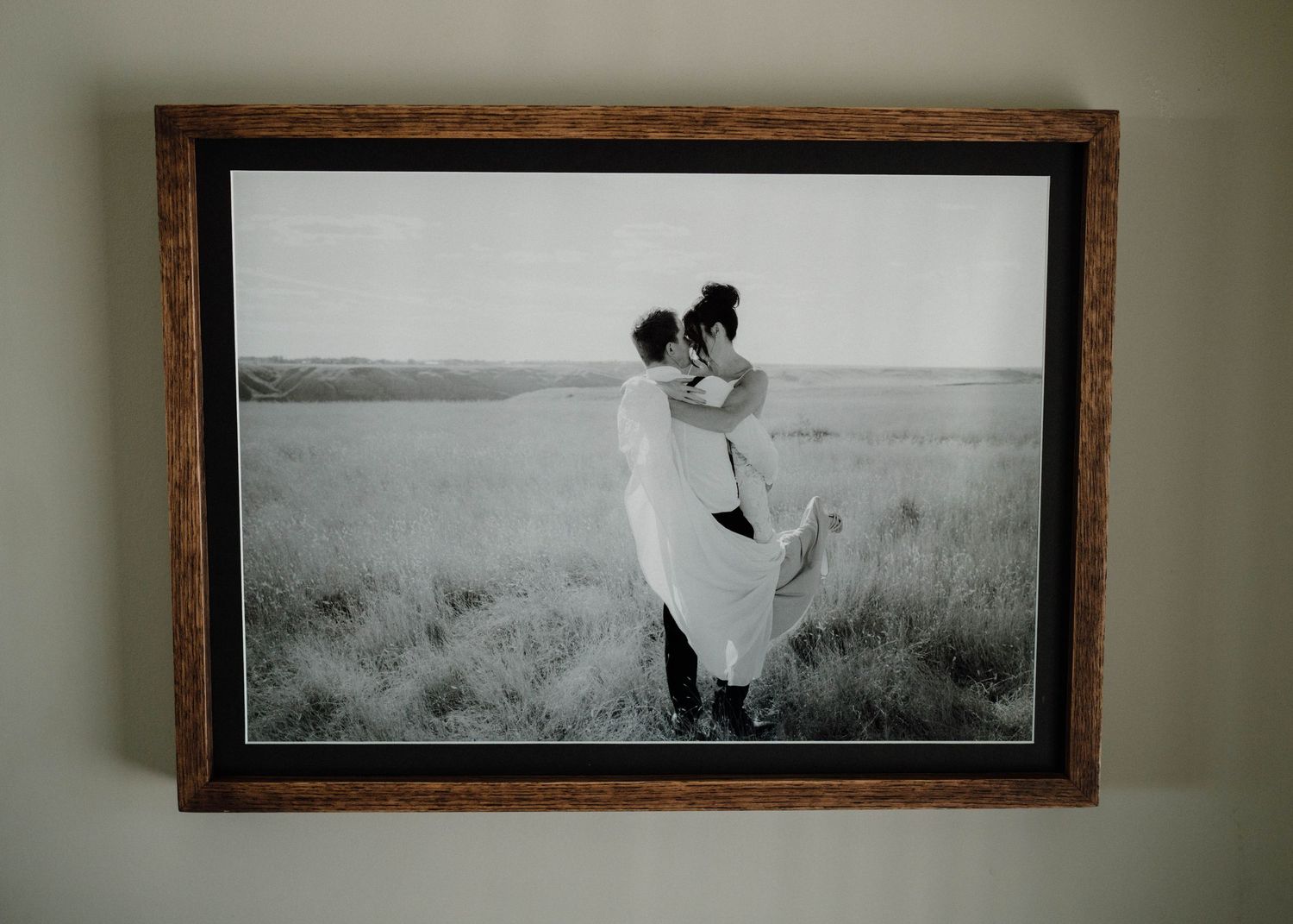 Black and white romantic couple portrait in rustic dark wood frame on neutral wall.
