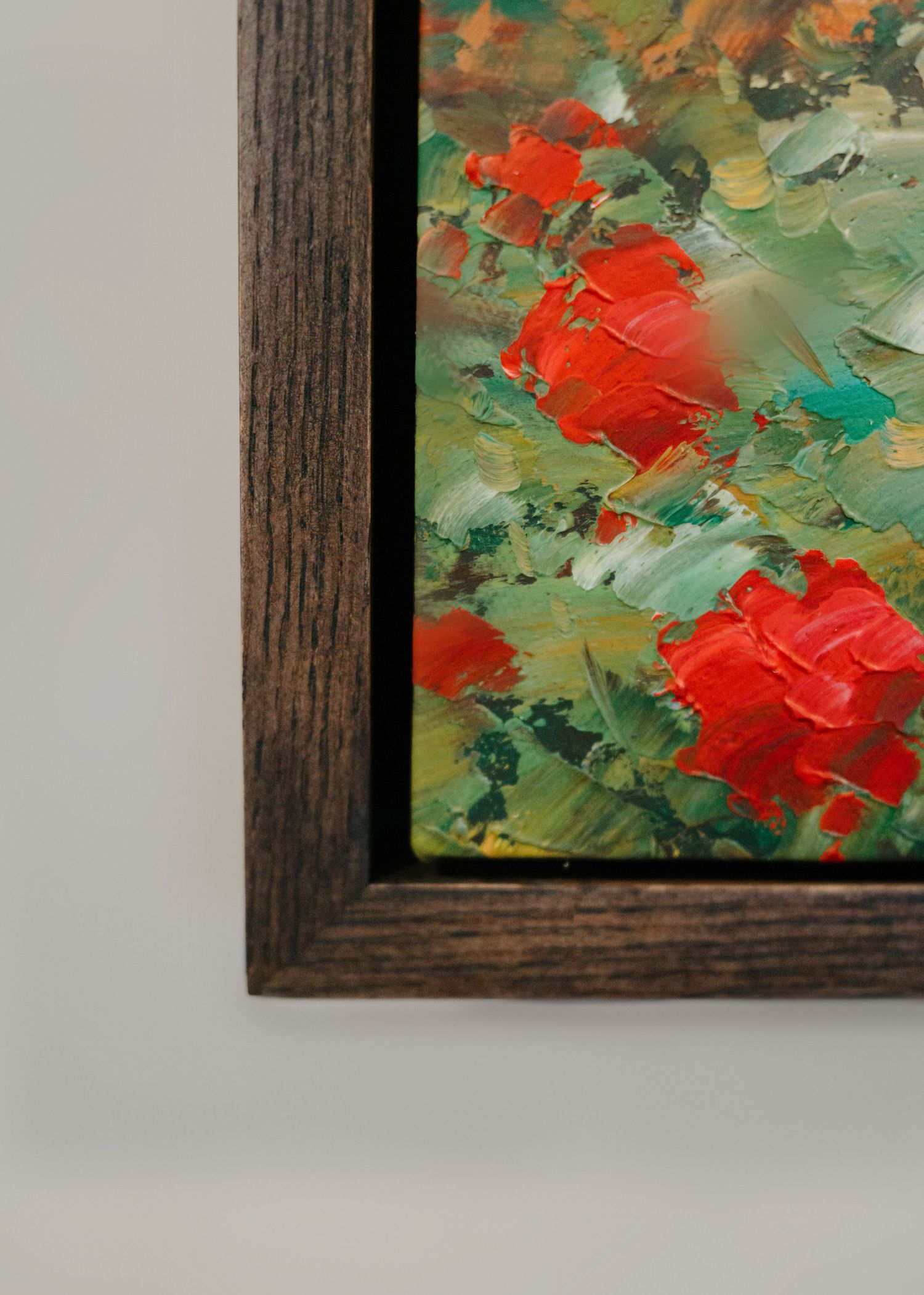 Close-up of a framed impressionist oil painting featuring vibrant red flowers with bold brushstrokes on a green background.