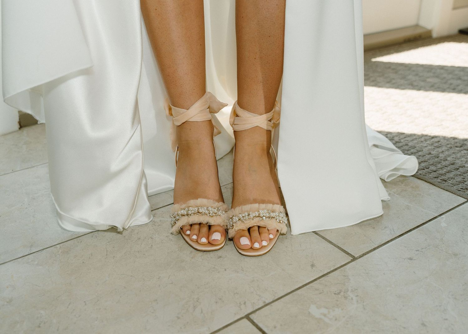 Bride wearing elegant beige strappy heeled sandals with fringe detail, paired with a flowing white wedding gown.