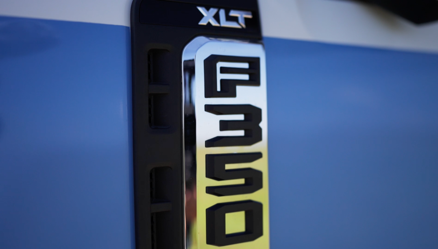 Close-up of a Ford F-350 XLT badge emblem on a blue truck door panel.