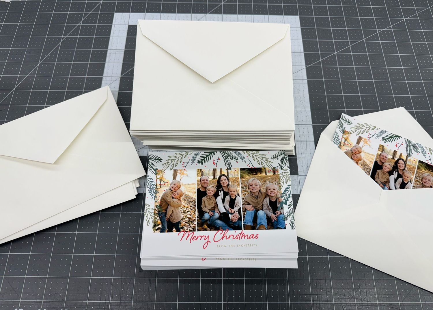 Christmas photo cards with family portrait reading Merry Christmas, displayed with white envelopes in a box.