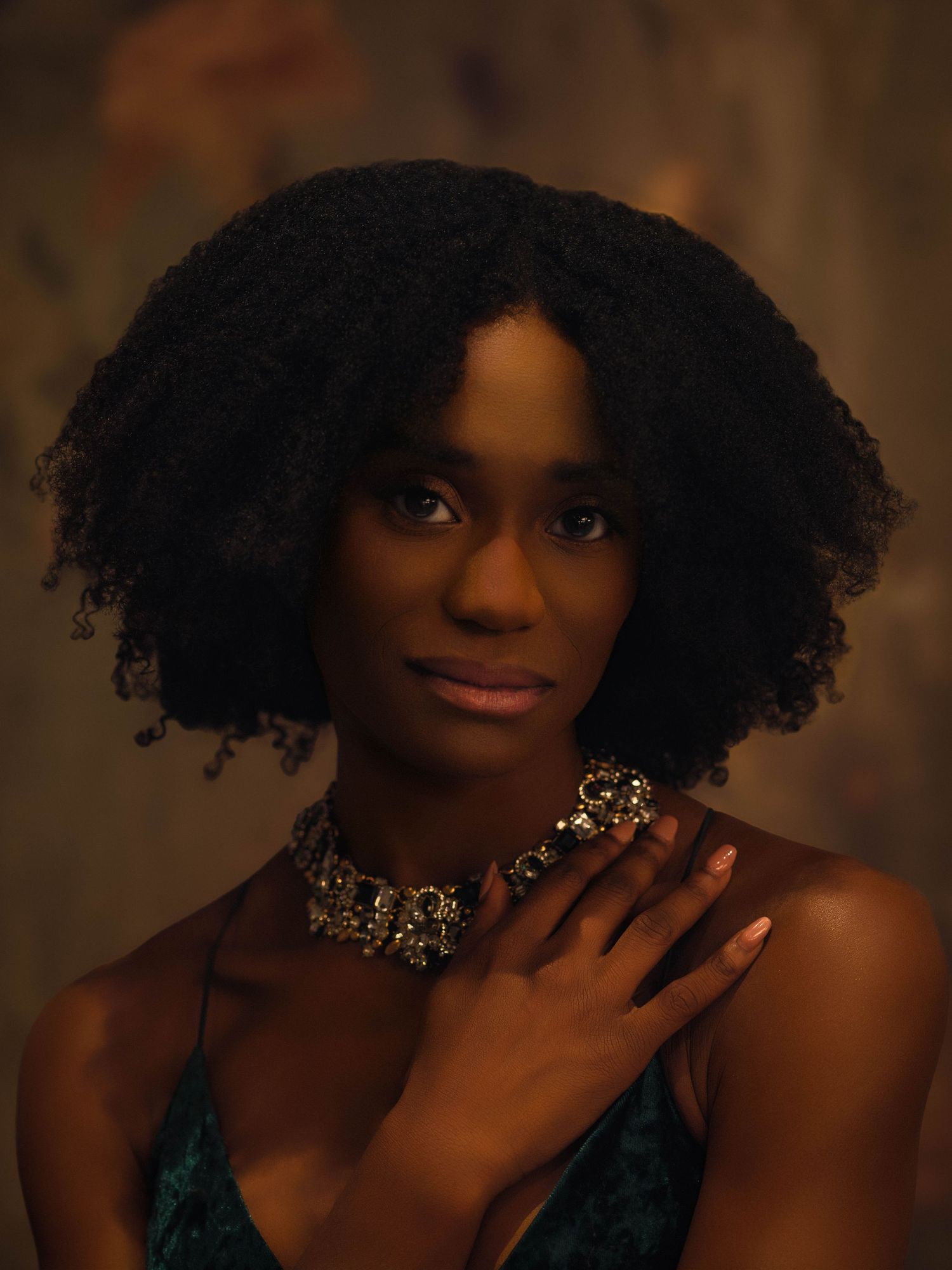 Black woman with natural curly hair wearing jeweled necklace and earrings in a moody fine art portrait in ATL.