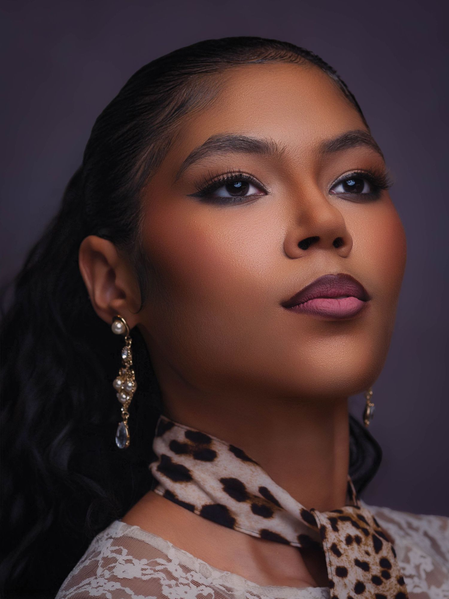 A young woman with elegant makeup, pearl earrings, and leopard print scarf poses in refined editorial portraiture in Marietta