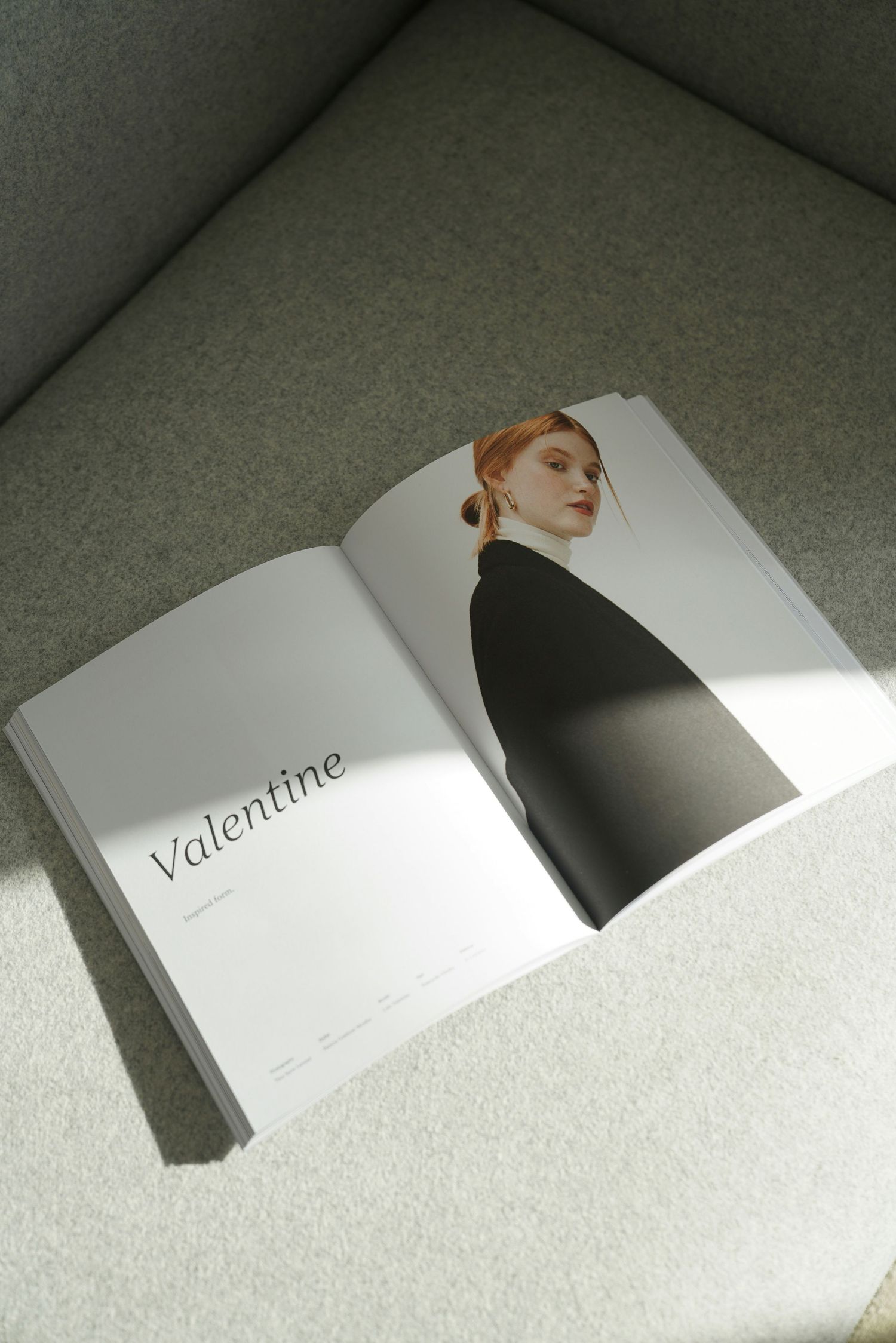 Open magazine spread titled Valentine featuring a minimalist portrait of a red-haired woman in a black outfit on a sofa.