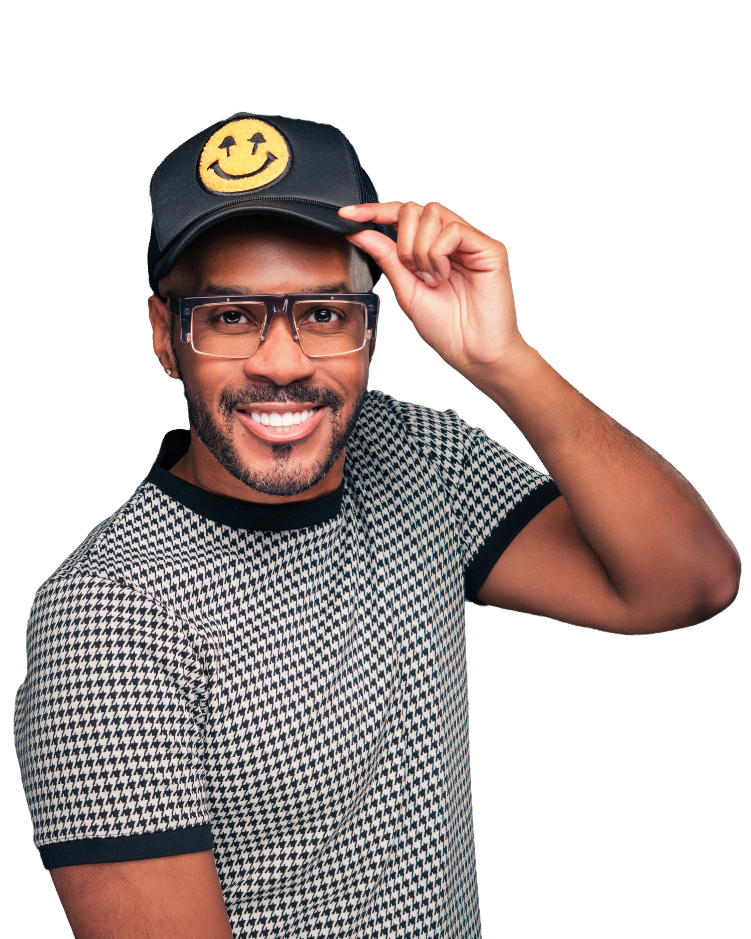 Smiling man wearing a black smiley face cap and houndstooth shirt, tipping his hat while wearing clear glasses.