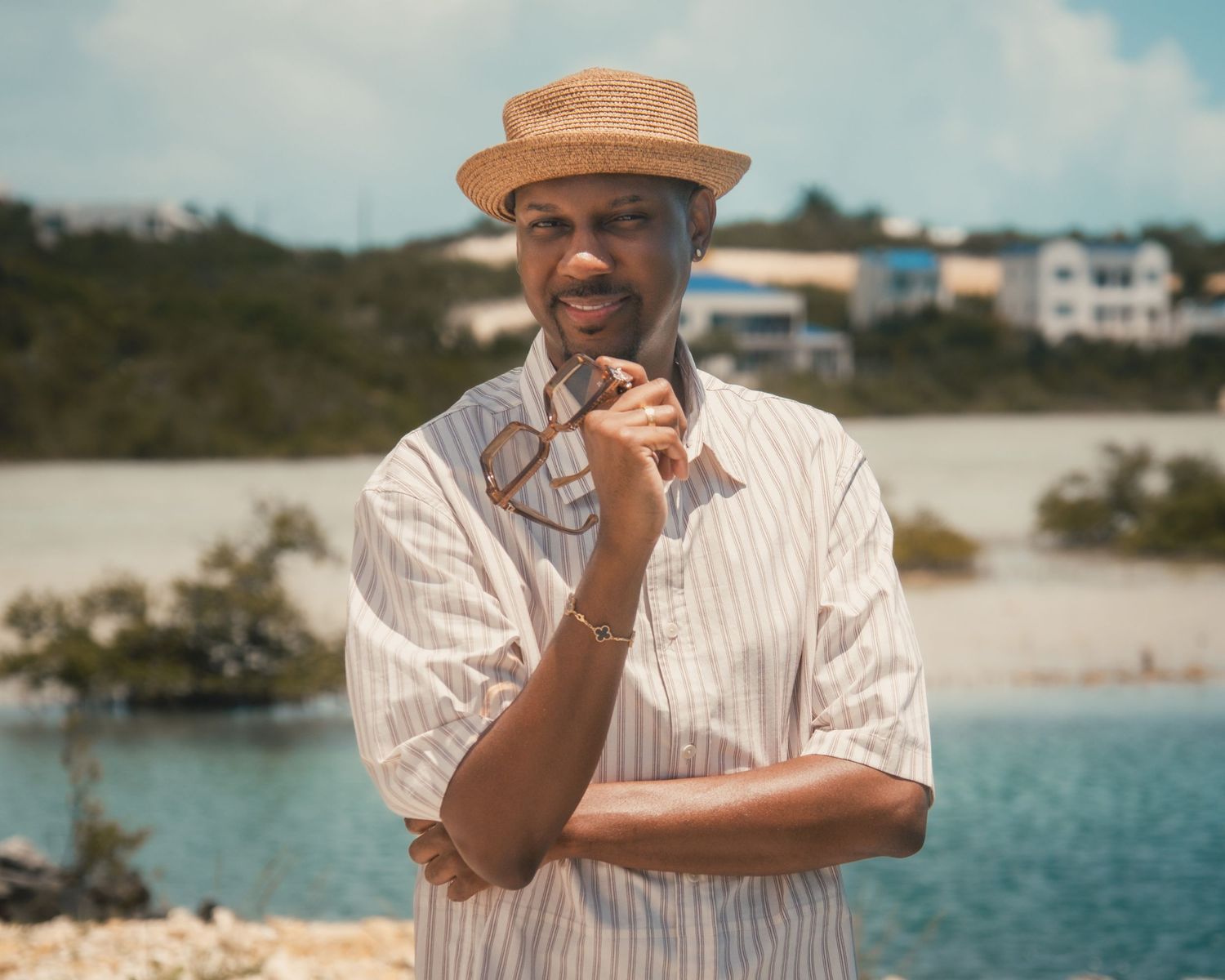 Man in straw boater hat and striped shirt posing at scenic cinematic tropical waterfront location captured by Atlanta cinematic photographer