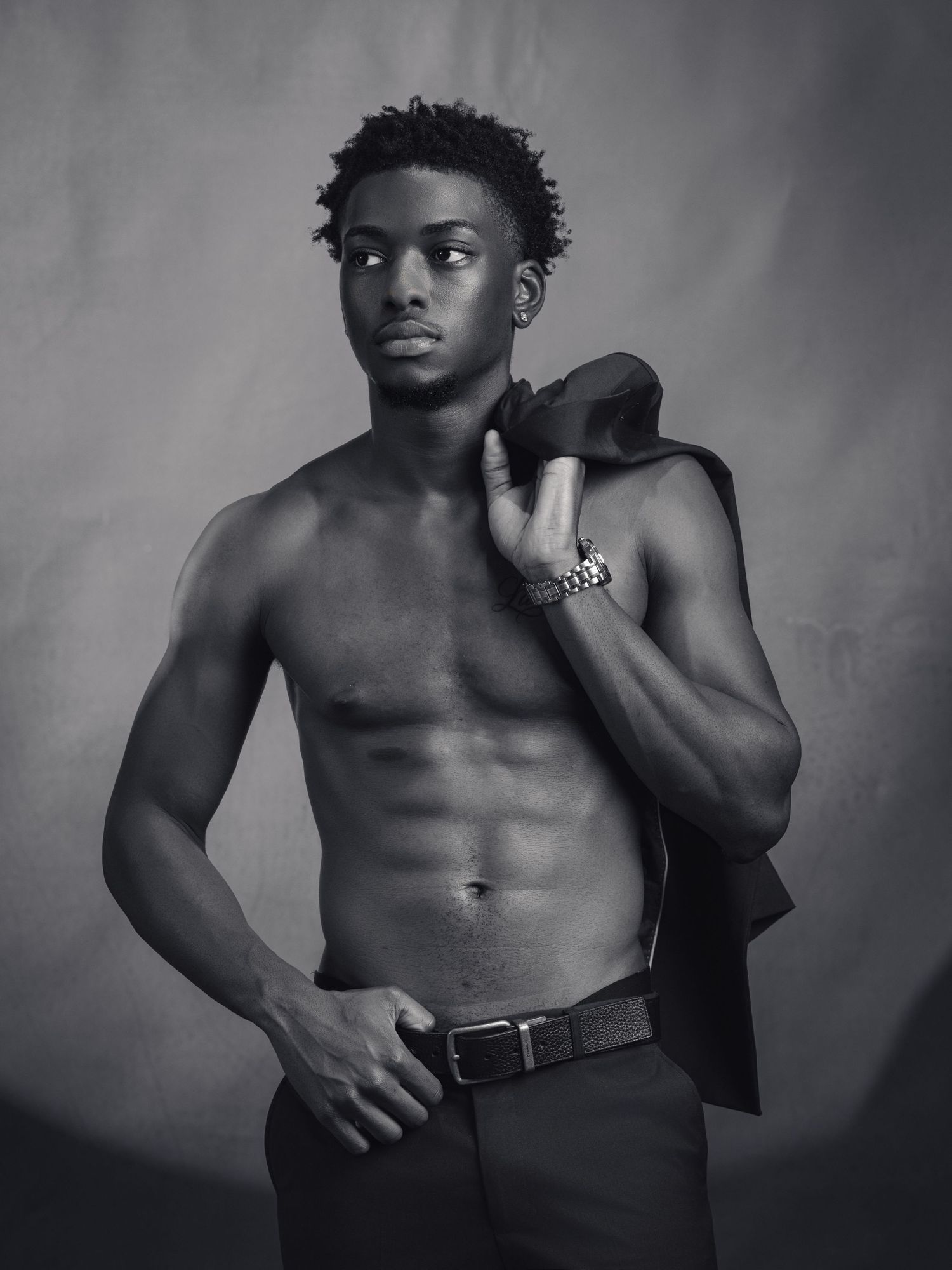 Black and white portrait of a shirtless athletic young man holding a jacket over his shoulder in luxury fine art photo