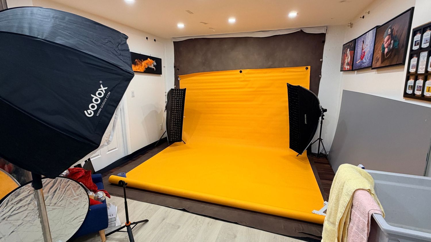 Professional photography studio setup with orange backdrop and Godox softbox lighting equipment.