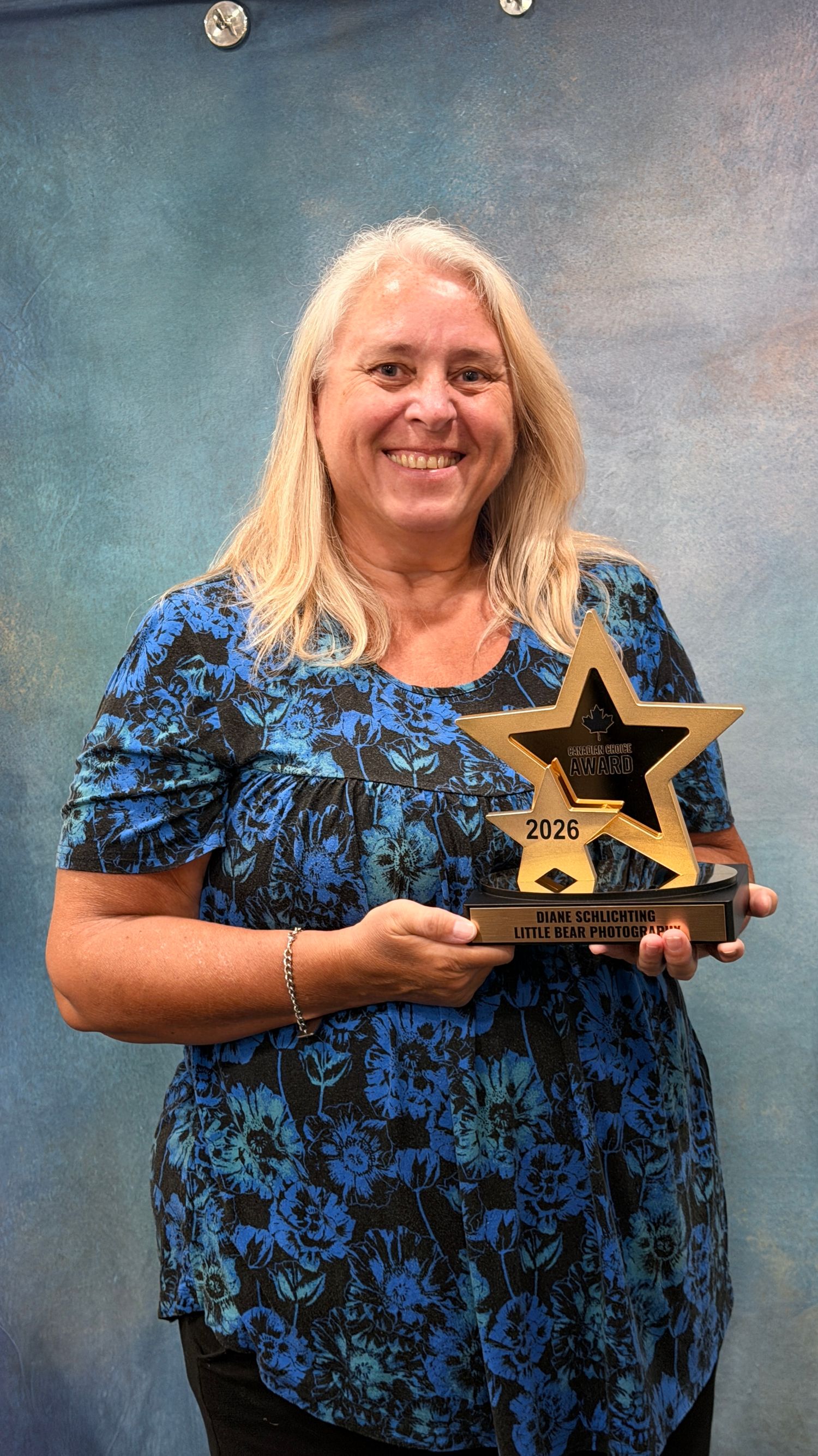 Woman smiling and holding a gold star-shaped award trophy dated 2026 at an indoor ceremony.