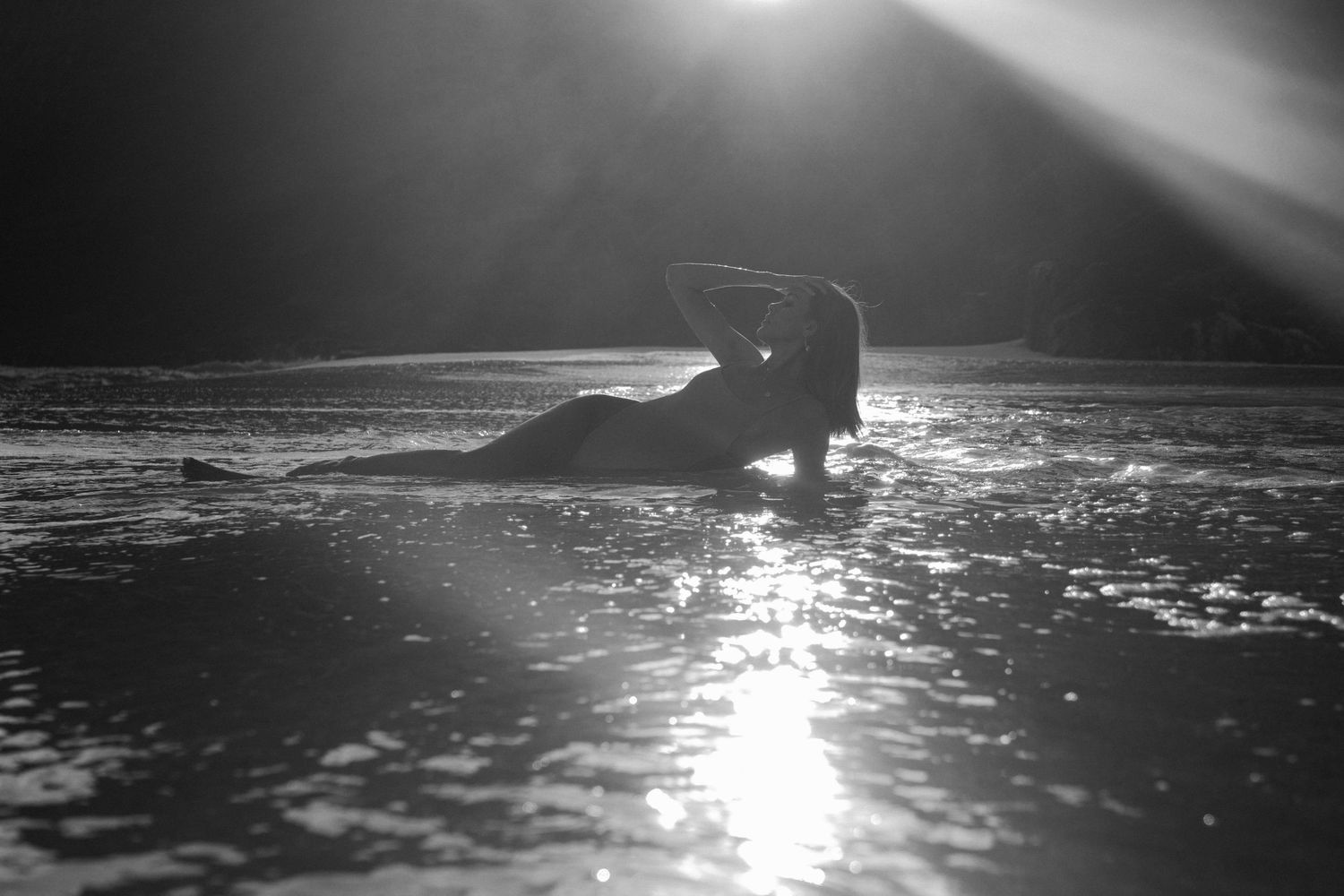 Black and white silhouette of a person posing on a reflective surface with dramatic backlight.