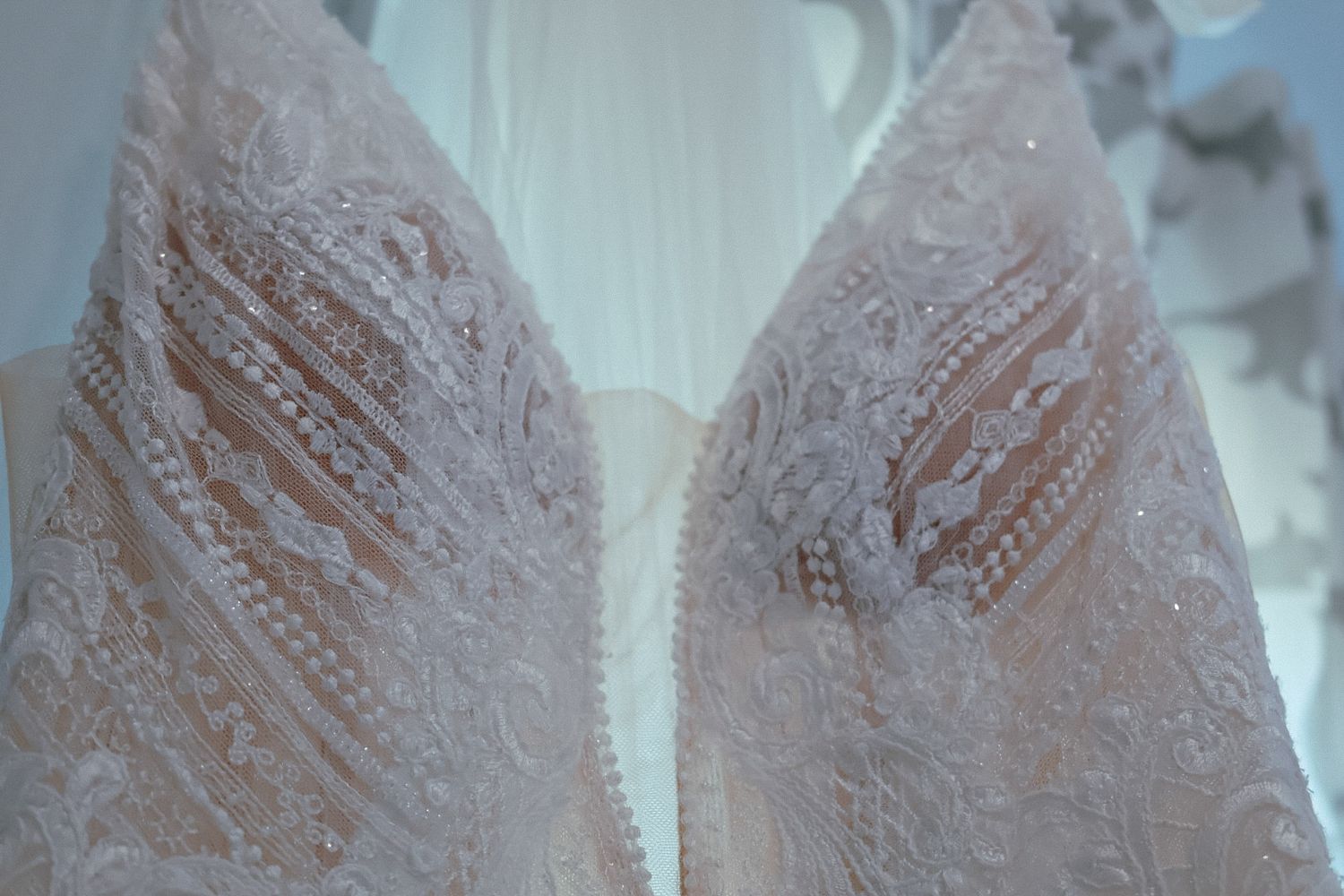 Detailed shot of a lace wedding gown hanging elegantly, captured with the airy and timeless style of Covered in Faith Photography.
