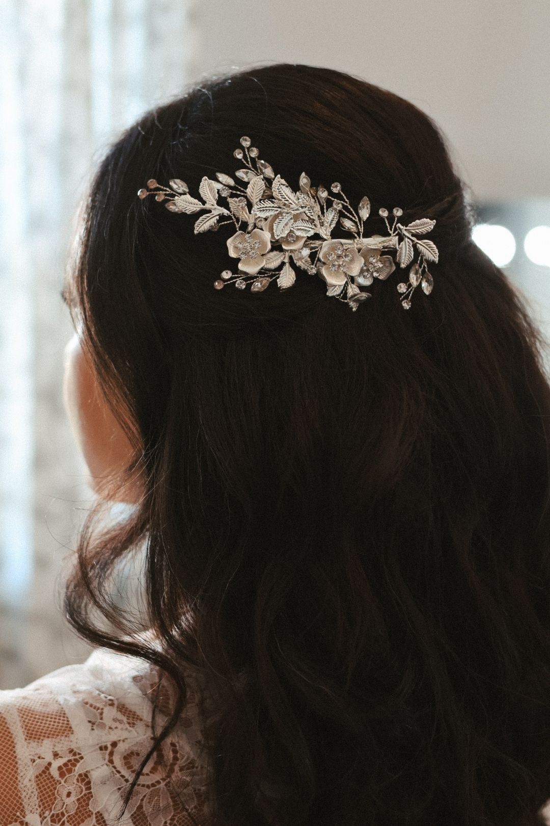 Close-up of a bride's hairstyle featuring a shimmering crystal floral hairpiece, reflecting a classic and romantic bridal aesthetic.