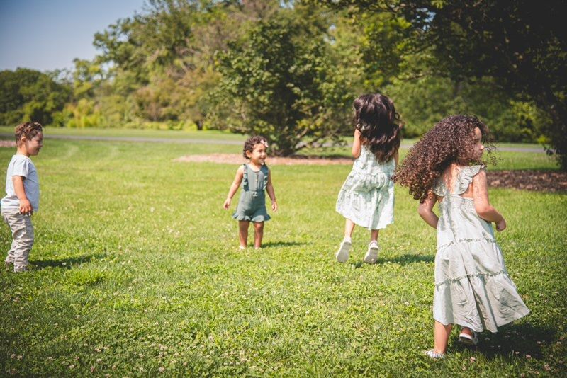 Four young children playing and running through a sun-drenched green field, capturing a sense of joyful wonder and childhood freedom.