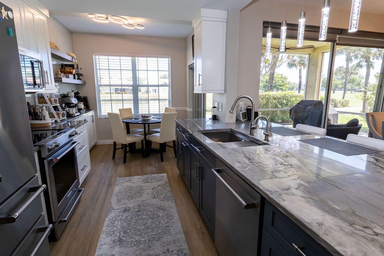 Gourmet kitchen with gray island, marble countertops, stainless steel appliances, and breakfast nook.