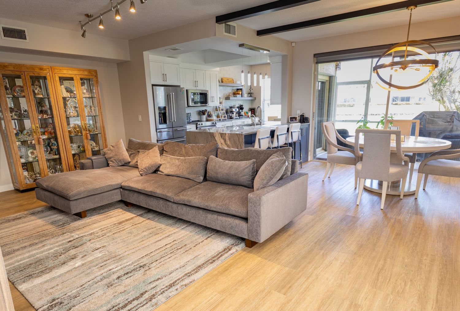 Open-concept living room with sectional sofa, hardwood floors, and modern kitchen in background.
