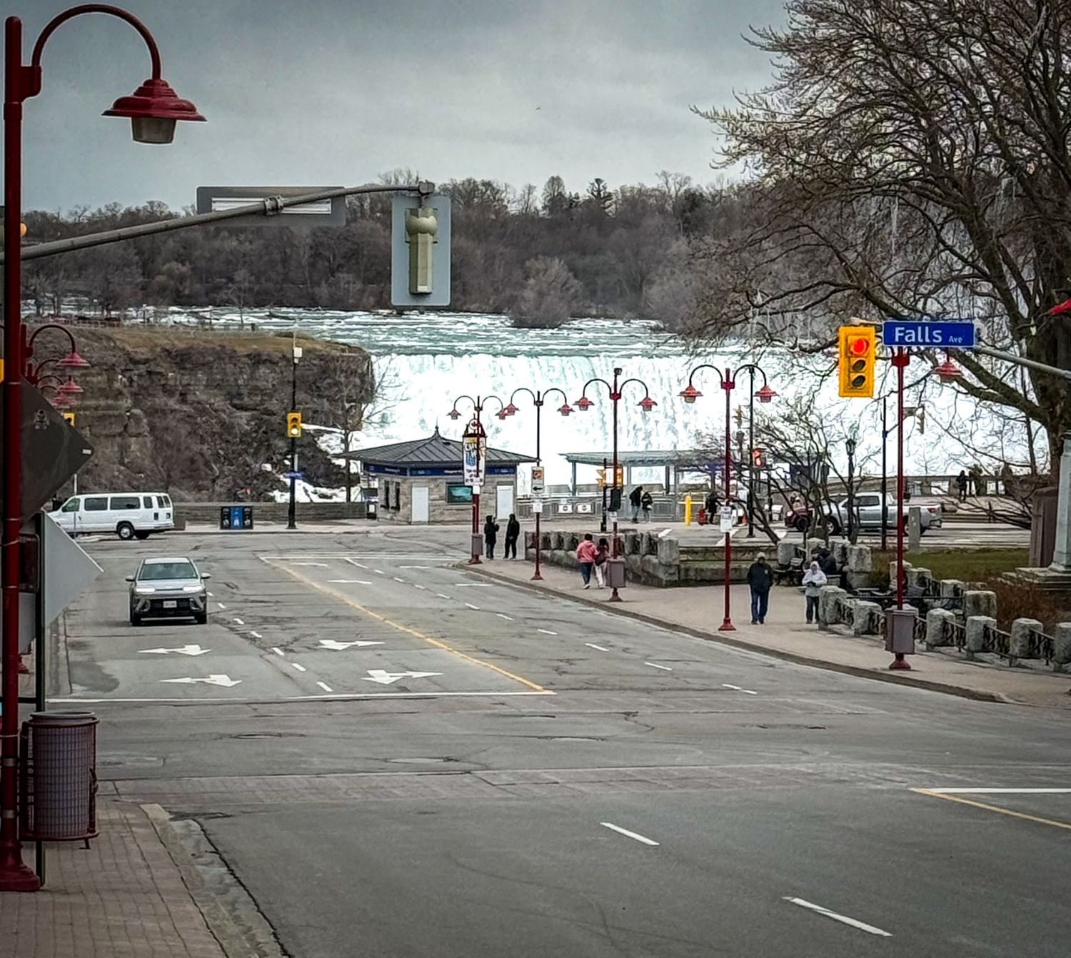 Street view leading to Niagara Falls tourist area with frozen waterfall visible in background.
