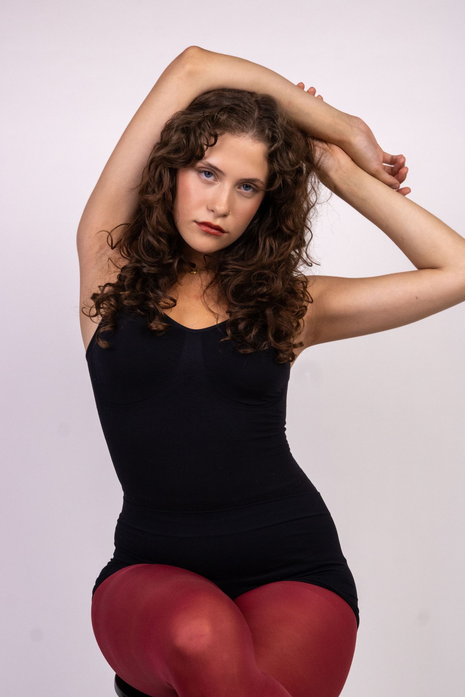 Mulher sentada, com os braços levantados acima da cabeça.
