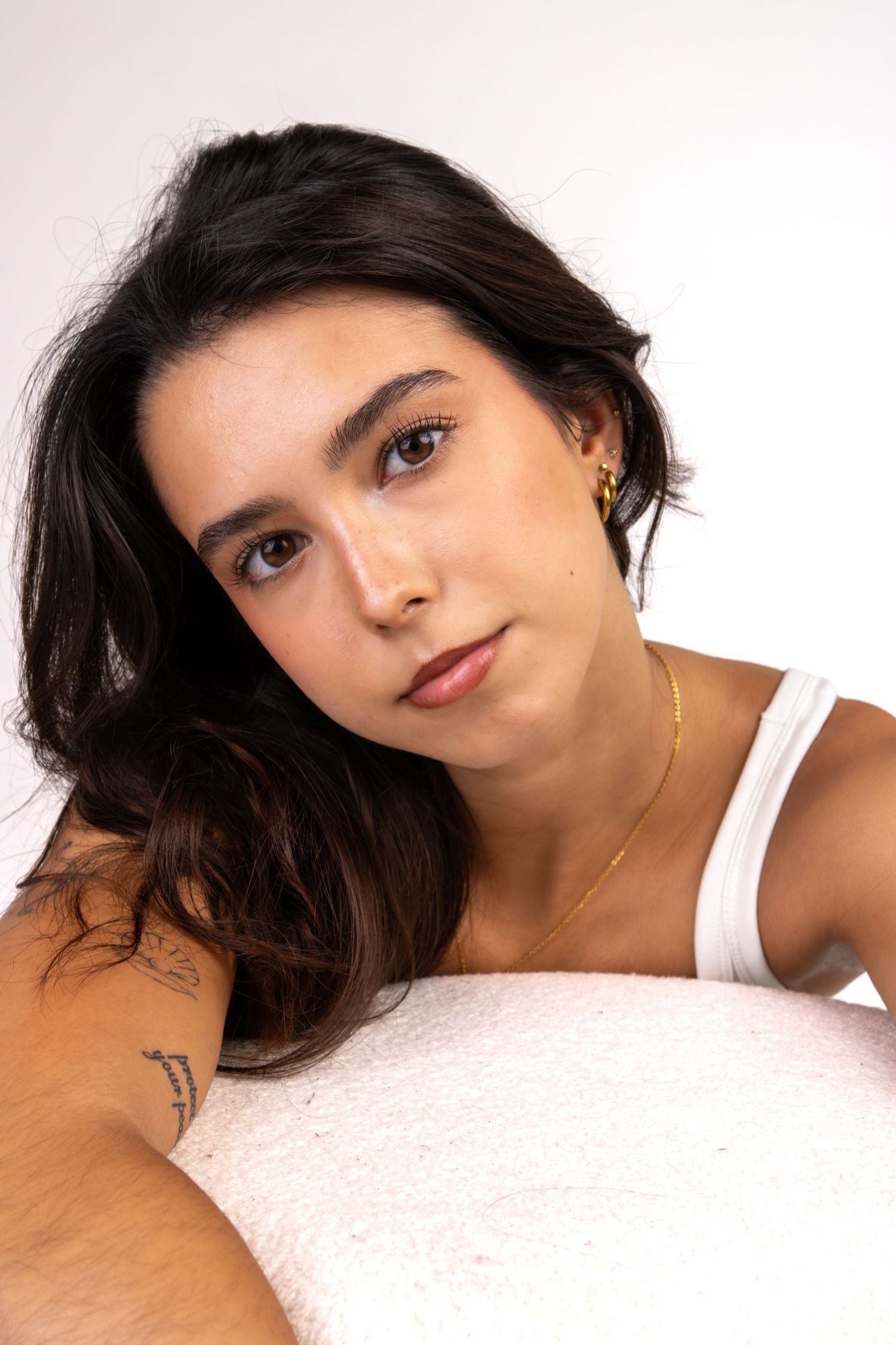 Retrato de uma mulher de cabelo escuro, deitada e apoiada numa almofada.