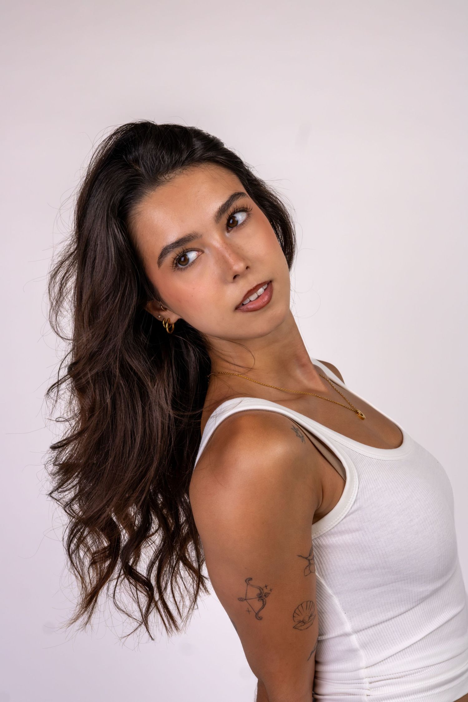 Retrato de uma mulher de cabelo comprido, usando top branco.