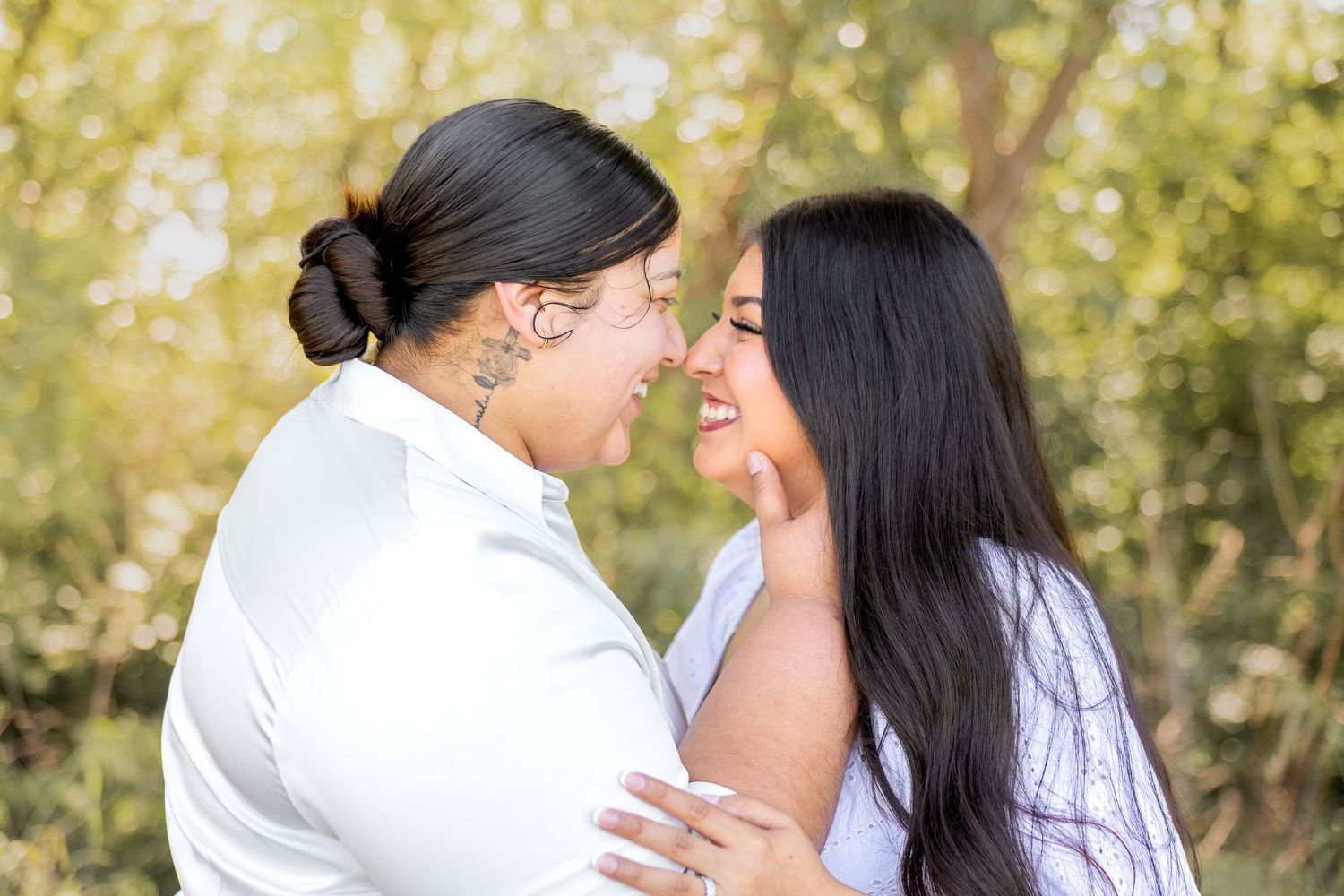Two women sharing a joyful close moment together in a green outdoor setting.