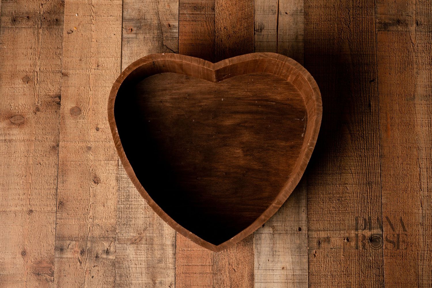 Heart-shaped wooden bowl on rustic reclaimed wood background, perfect for home decor or Valentine's Day gifts.