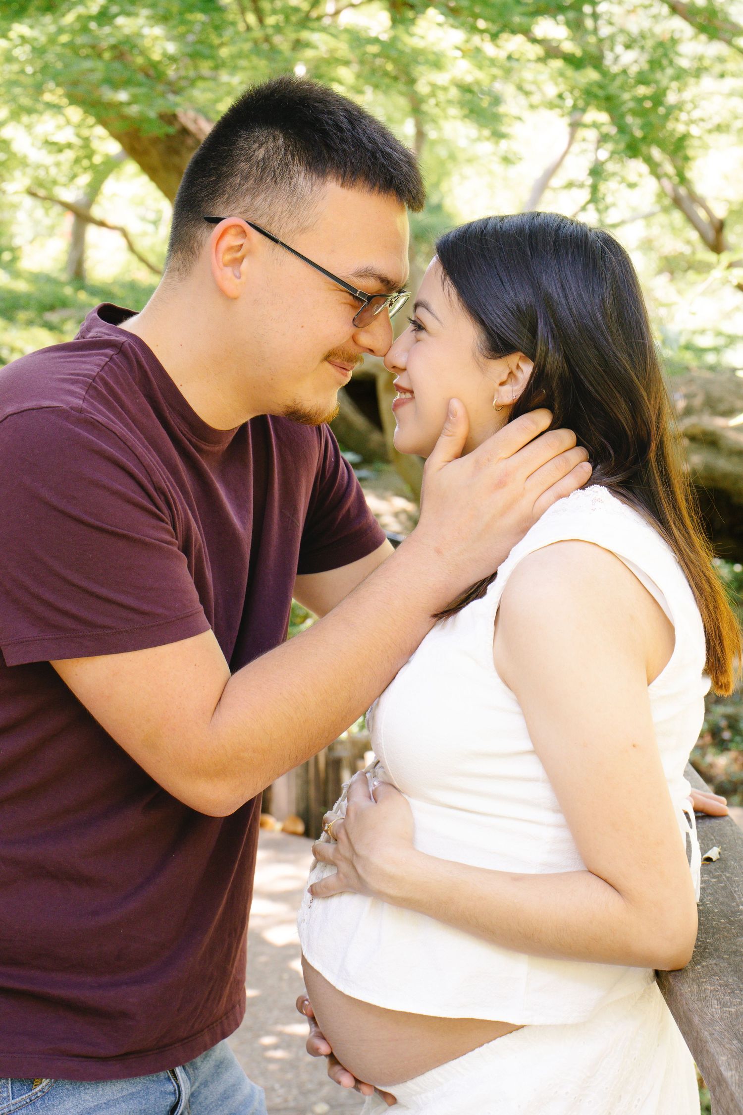 Loving couple sharing a tender moment nose-to-nose during outdoor maternity photography session.