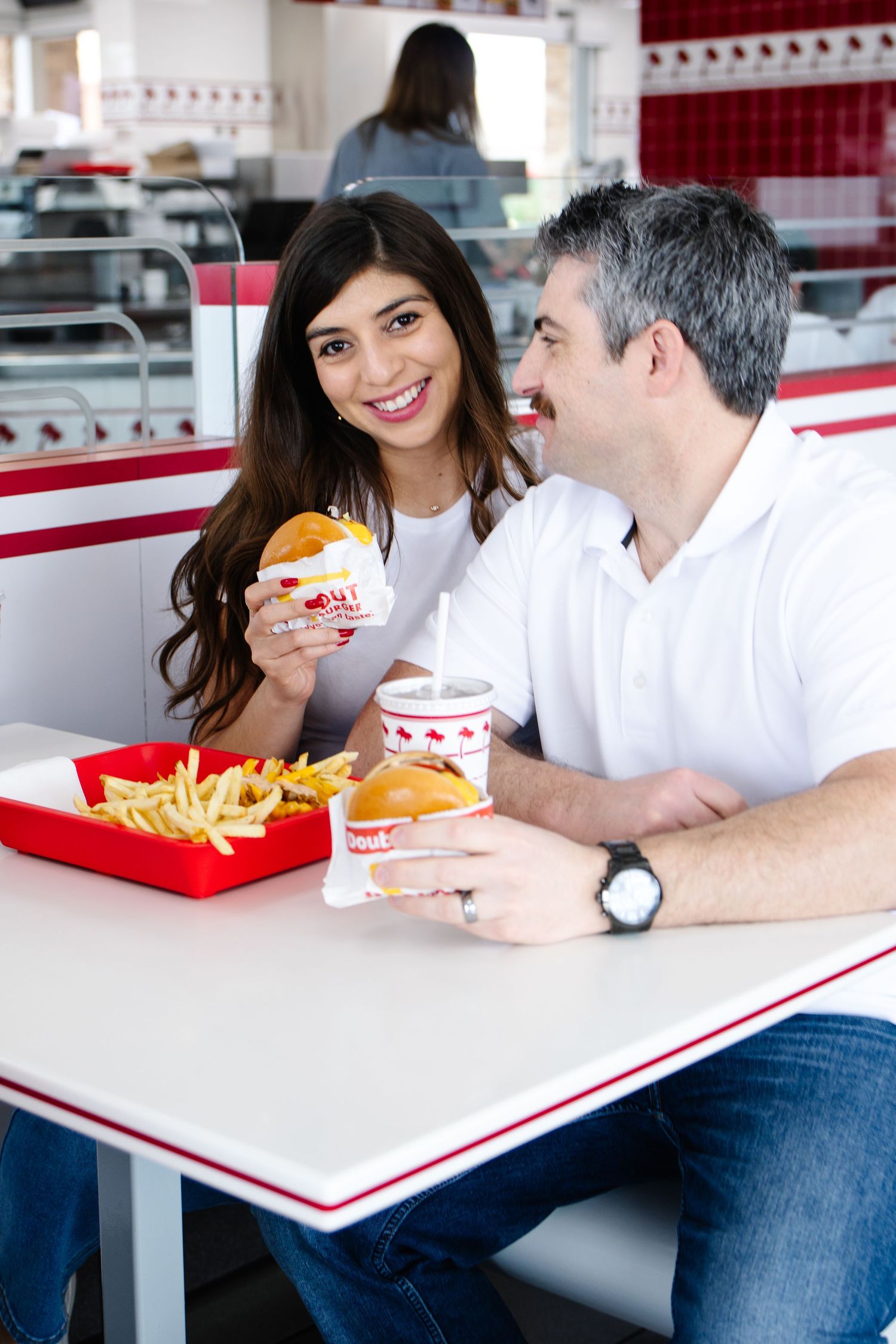 Smiling couple enjoying burgers and fries at an In-N-Out Burger restaurant on a casual date.