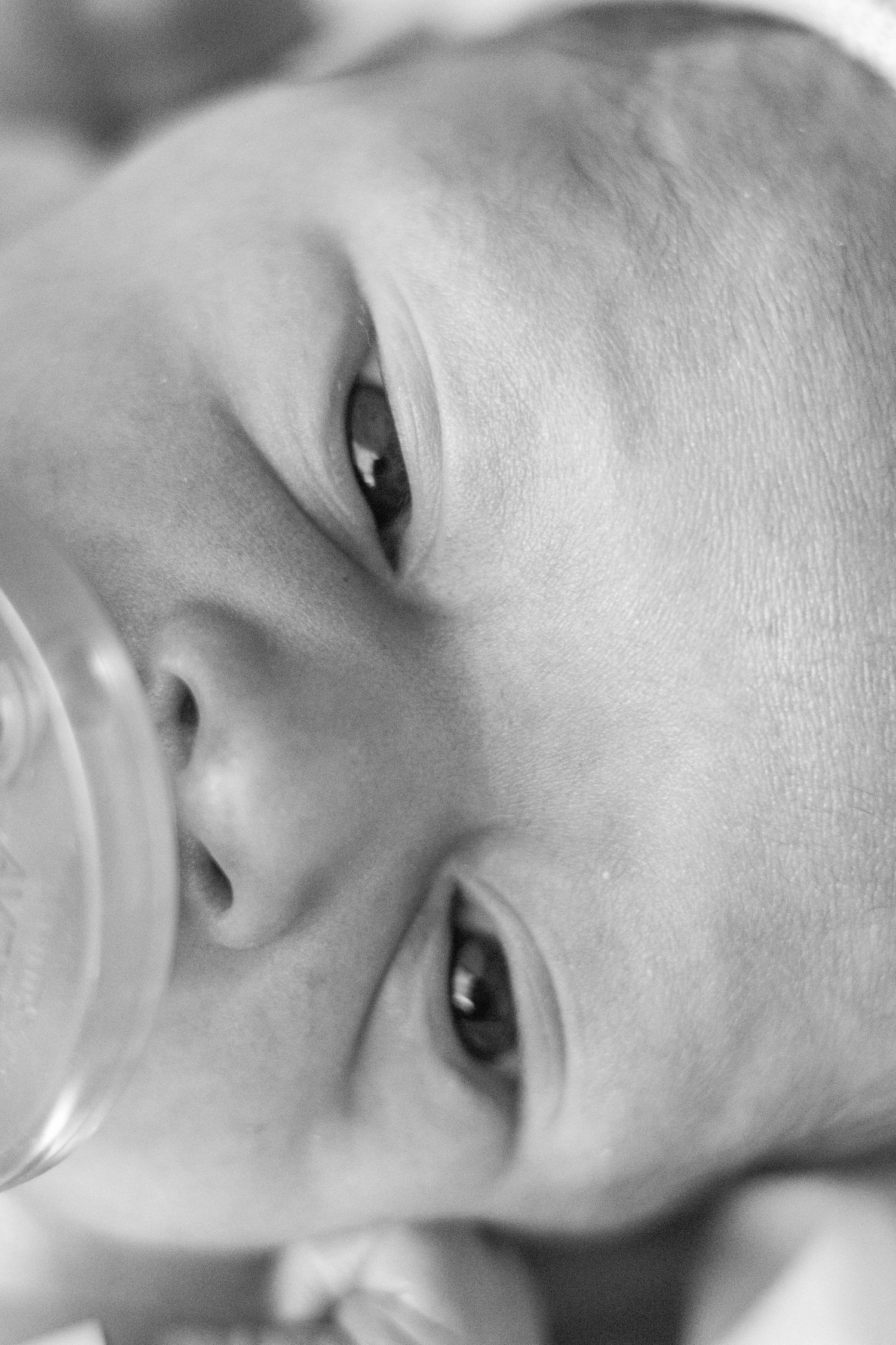 Extreme close-up black and white portrait of a newborn baby's face with open eyes.