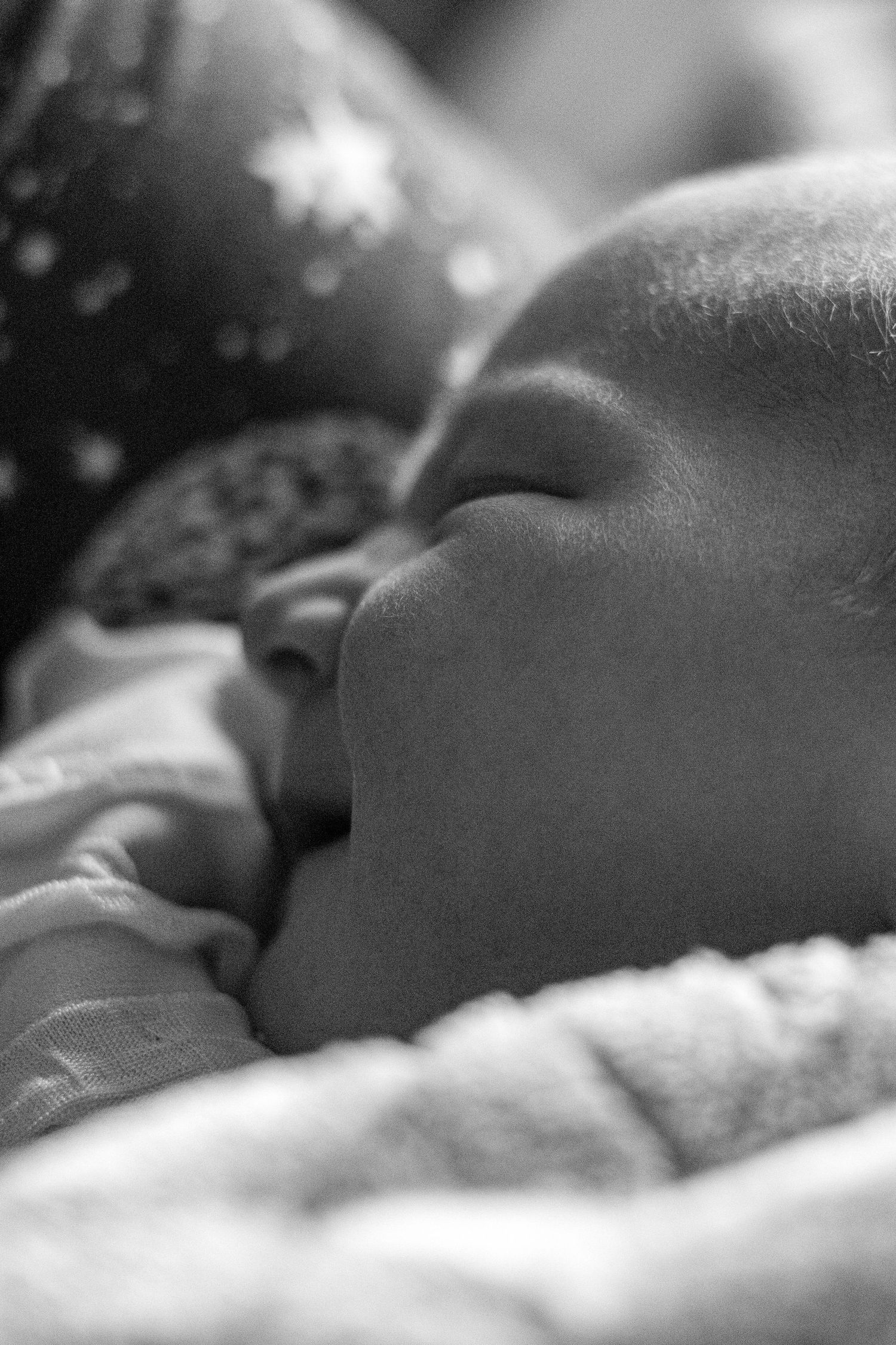Peaceful sleeping newborn baby close-up profile, black and white hospital photography.