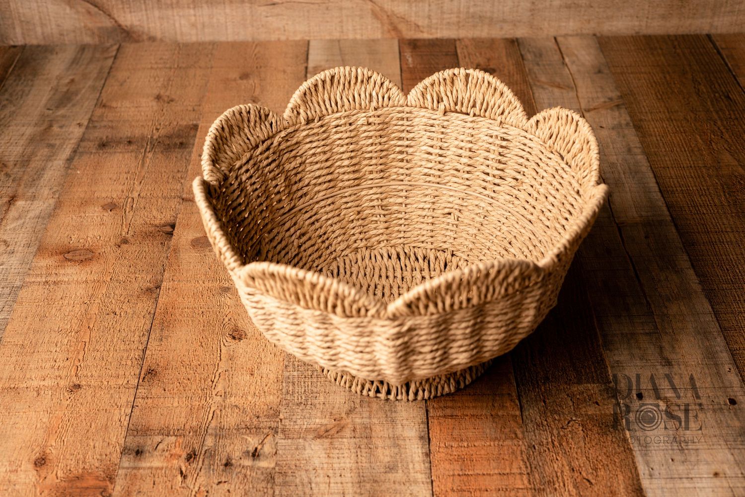 Handwoven rattan wicker basket with scalloped edges on rustic wood surface.