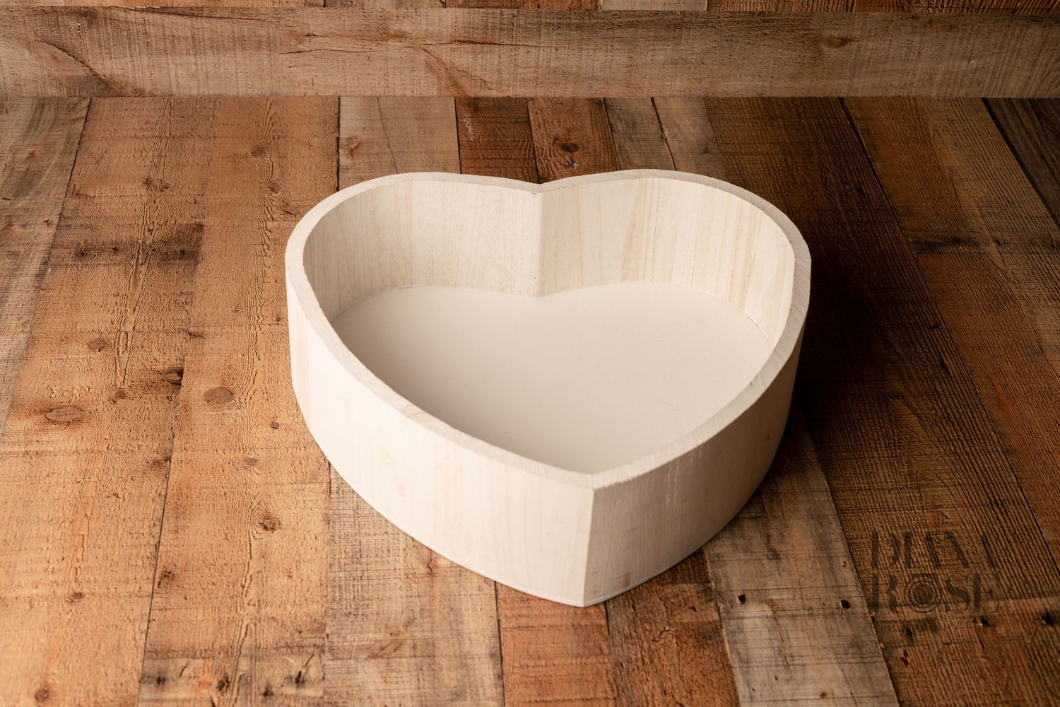 Heart-shaped wooden bowl on rustic wood surface.