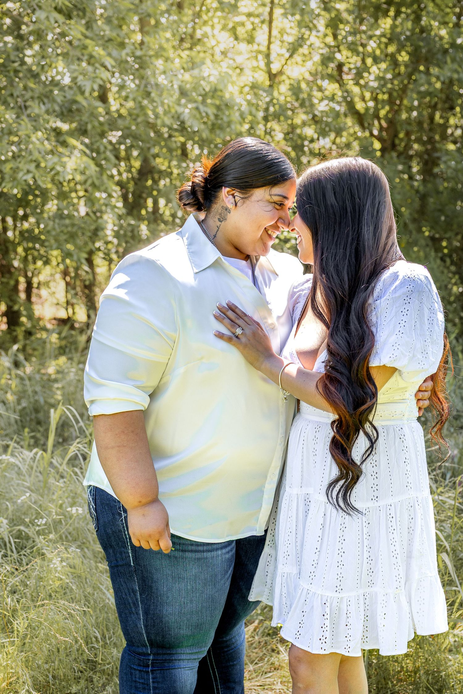 Couple sharing a romantic nose-to-nose moment in a sunlit green field.