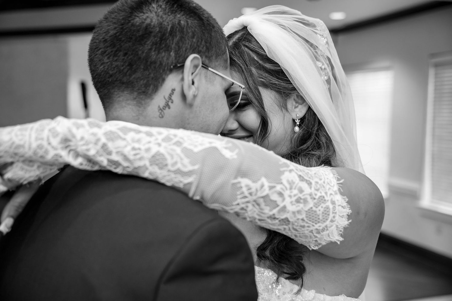 Bride and groom share emotional first look hug in black and white wedding photography.