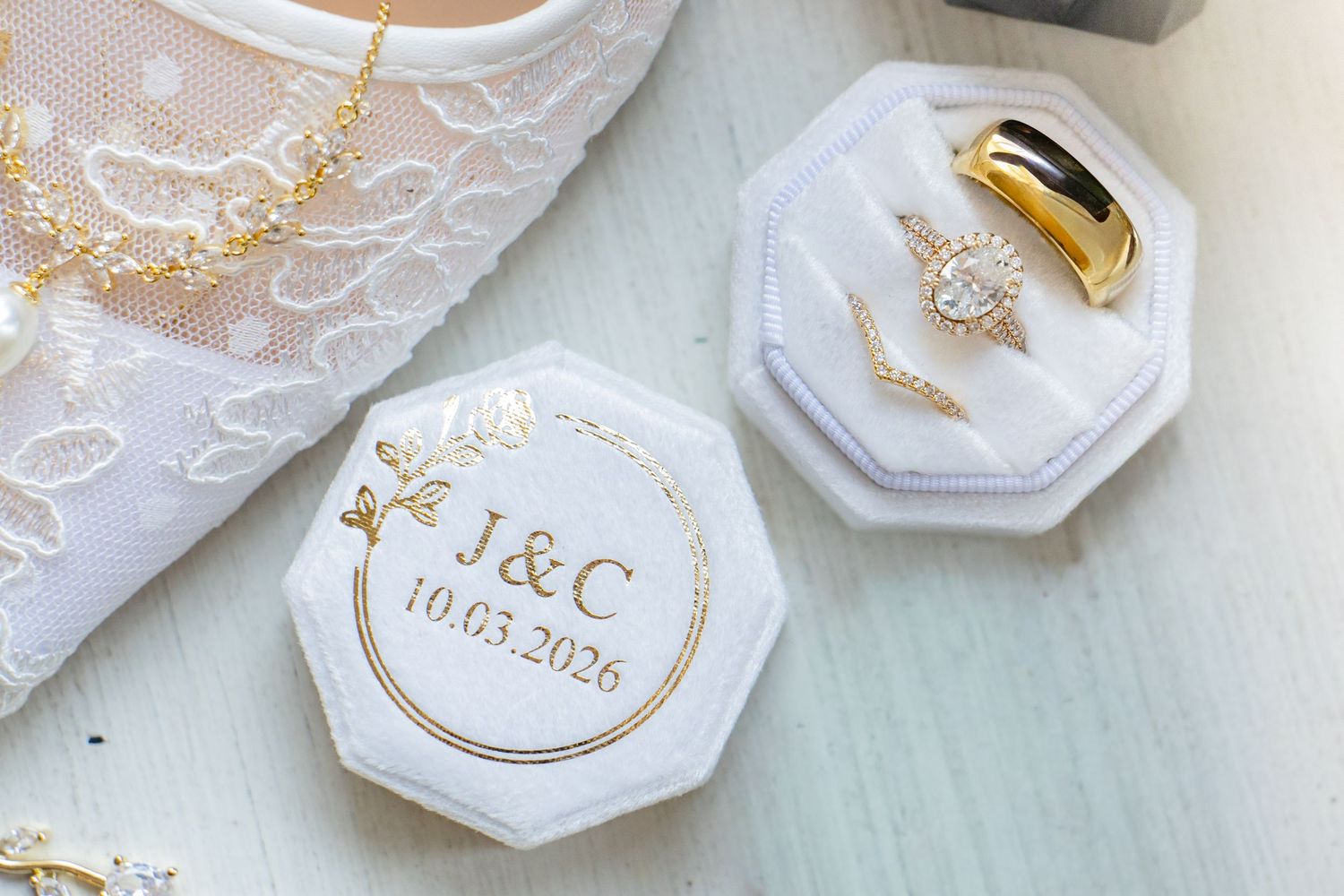 White octagonal wedding ring box with gold J&C monogram and date 10.03.2026, displayed with rings and bridal accessories.